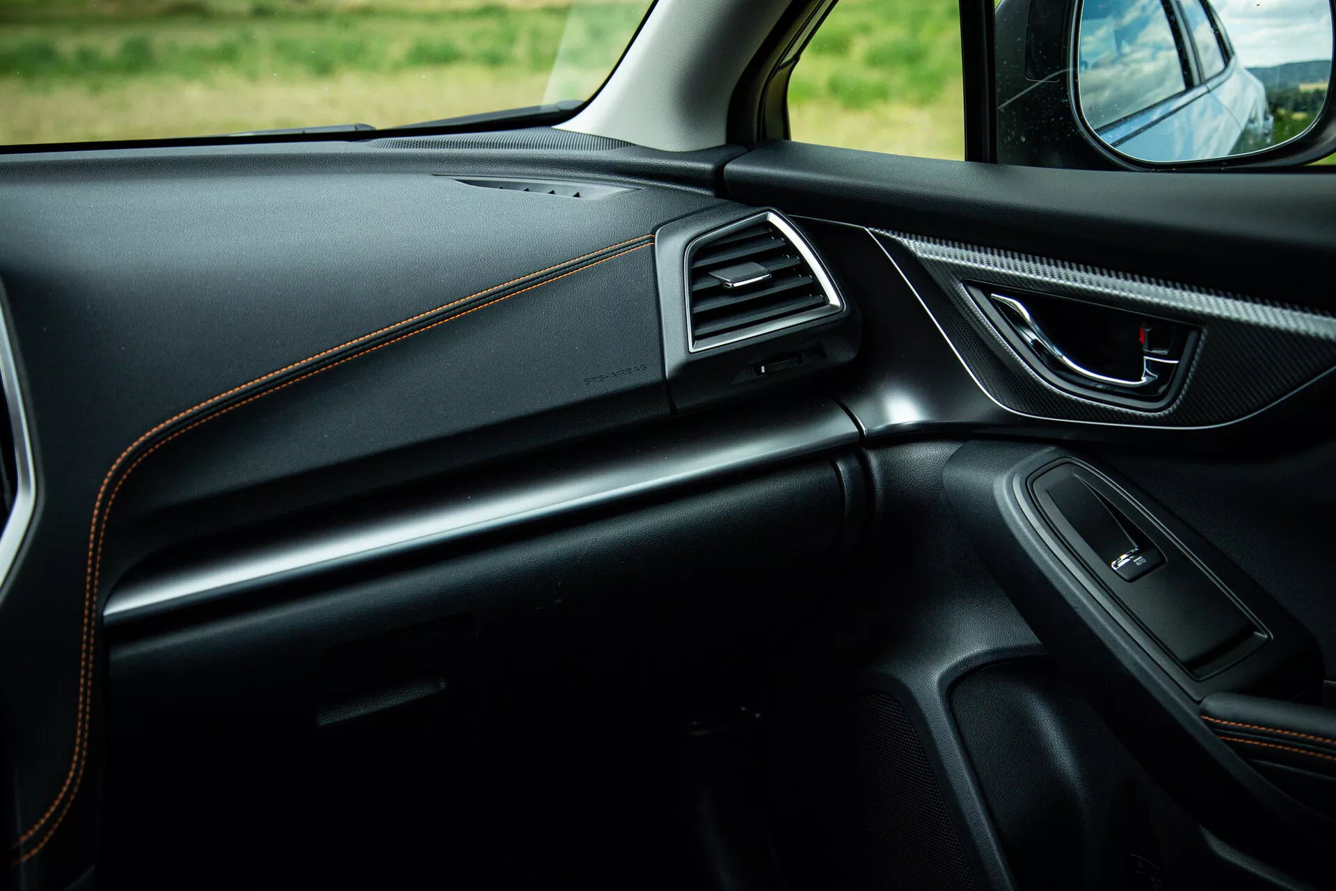Interiér Subaru XV 2021 so zameraním na stranu spolujazdca ukazujúci štýlový dizajn prístrojovej dosky s kontrastným štepovaním, ergonomickú kľučku dverí s ovládaním elektriky, integrovaný reproduktor, vzduchové otvory s chromovým akcentom a ambientné osvetlenie