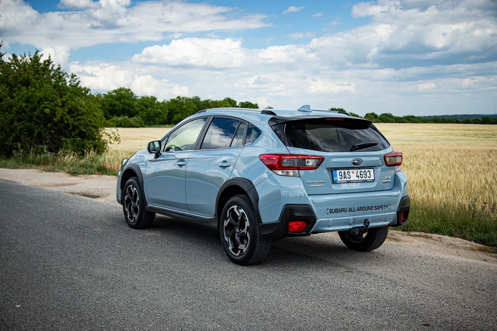 Svetlomodré kompaktné SUV Subaru XV 2021 odfotografované z zadného trojštvrťového uhla so zreteľným akcentom na pravú stranu, dynamickou pózou na spevnenej ceste s jasným výhľadom na zadný spojler, zliatinové kolesá, zadné LED svetlá, označenie modelu, jednoduchú výfukovú špičku a potenciálne technologické funkcie