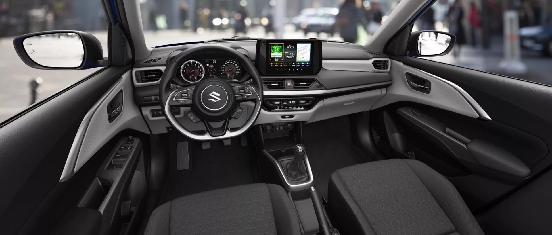 Interiér Suzuki Swift 2024 (7. generácia) z pohľadu zo zadného sedadla ukazujúci modernú palubnú dosku s ovládacími prvkami na volante, digitálnym prístrojovým panelom, centrálnym dotykovým infotainment systémom, ovládaním klímy, automatickou radiacou pákou a sofistikovanými materiálovými povrchmi