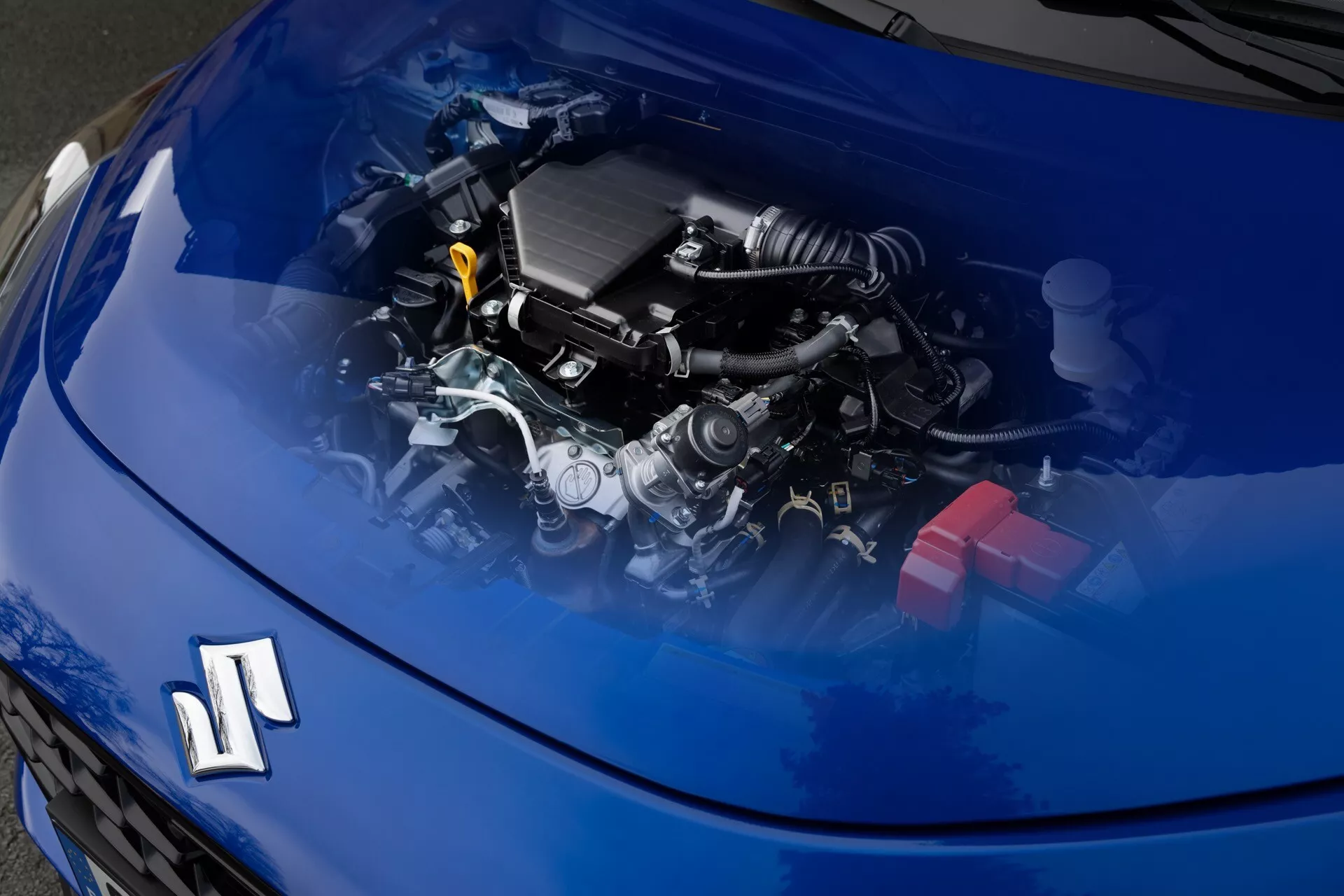 Koncepcia Suzuki Swift siedmej generácie 2024 s digitálne priehľadnou kapotou zobrazujúcou moderný spaľovací motor a komponenty z pohľadu spredu a zhora so sklonom k pravej strane