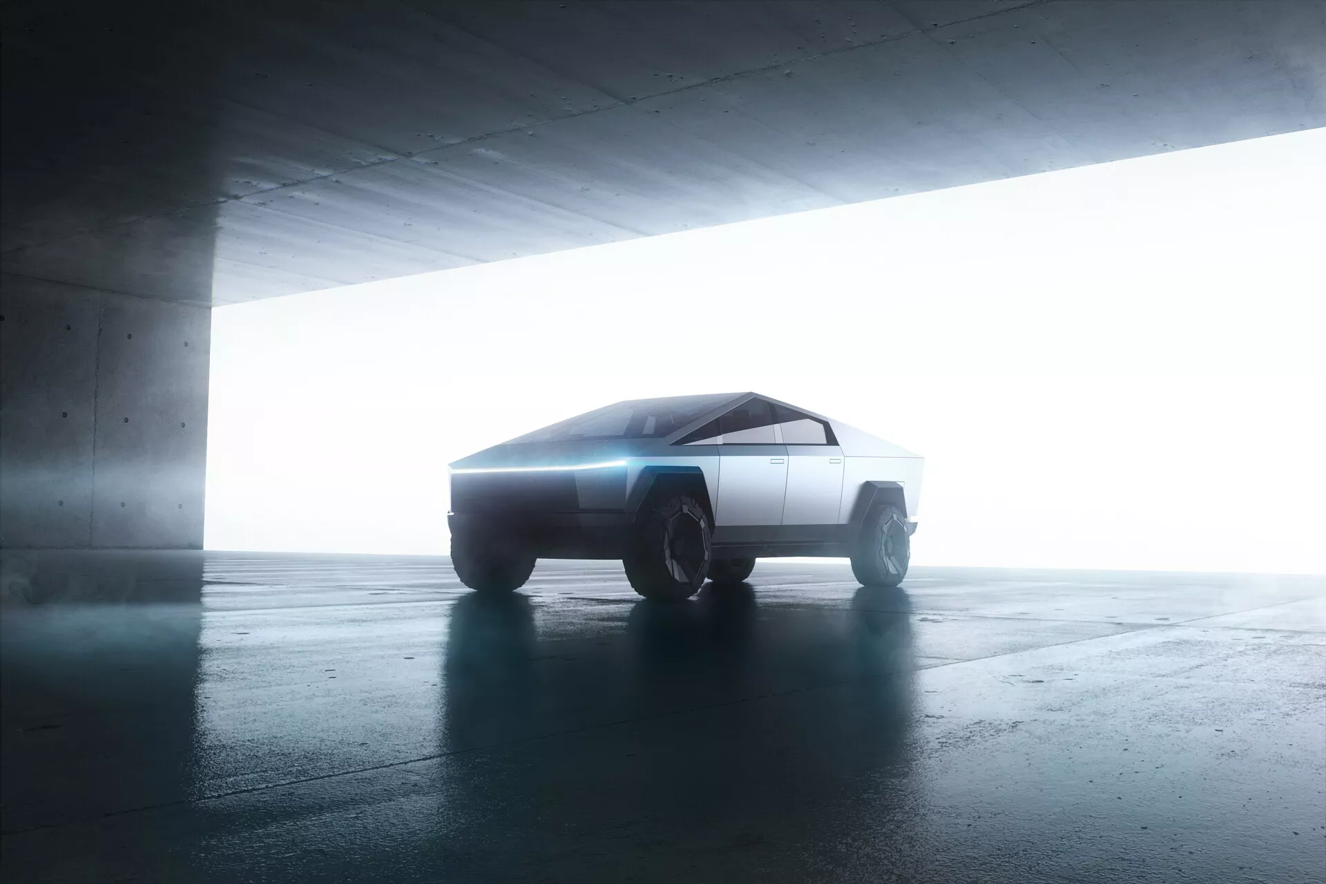 Bočný pohľad na Tesla Cybertruck 2021 v parkovacej garáži. Vozidlo s futuristickým, hranatým dizajnom je mierne naklonené smerom ku kamere a ukazuje svoje minimalistické, geometrické línie. Protisvetlo zvýrazňuje siluetu a vytvára efekt halo. Ostré, ploché povrchy a robustné off-road kolesá naznačujú pokročilú, pravdepodobne elektrickú pohonnú technológiu.