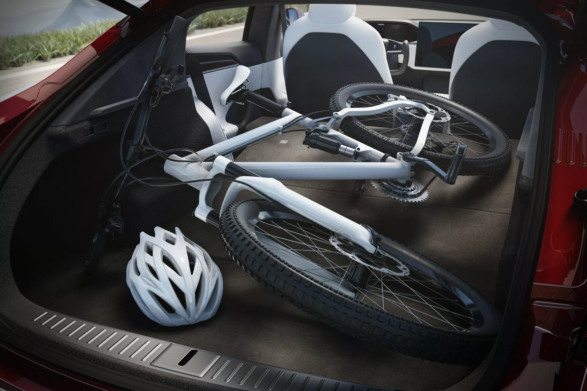 Detailný pohľad na otvorený kufor vozidla Tesla Model S 2016 (1. generácia facelift), fotografovaný z vysokého uhla. V kufri leží rozložený biely bicykel s viditeľným rámom a kolesami, vedľa ktorého sa opiera biela cyklistická prilba. Čierny interiér kufra a odolná, textúrovaná ochranná lišta pri nakladaní sú jasne viditeľné, čo zdôrazňuje praktické využitie a úložné možnosti vozidla na prepravu športového vybavenia.