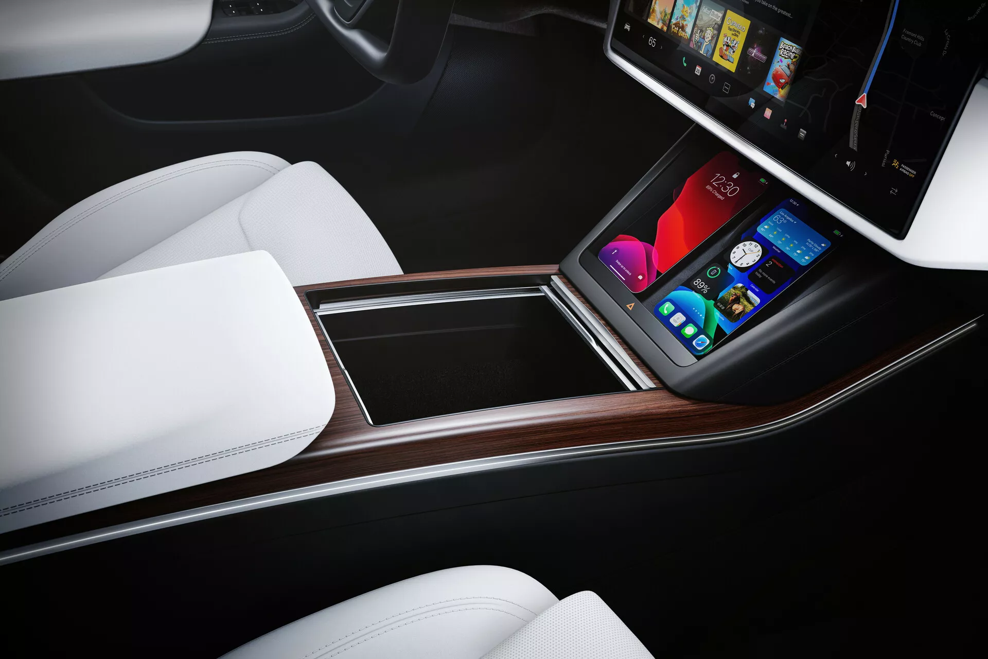 Pohľad na interiér Tesla Model S 2016 (1. generácia, facelift) zameraný na stredovú konzolu z nadhľadu, orientovaný na vodiča. Ergonomické usporiadanie s vertikálne orientovaným dotykovým displejom infotainment systému zobrazujúcim farebnú grafiku pre ovládanie klimatizácie, médií, navigácie a nastavení vozidla. Konzola je dokončená drevodekórom, bielymi sedadlami pripomínajúcimi kožu a dvojfarebným dizajnom, zdôrazňujúci luxus a minimálne množstvo fyzických ovládačov.