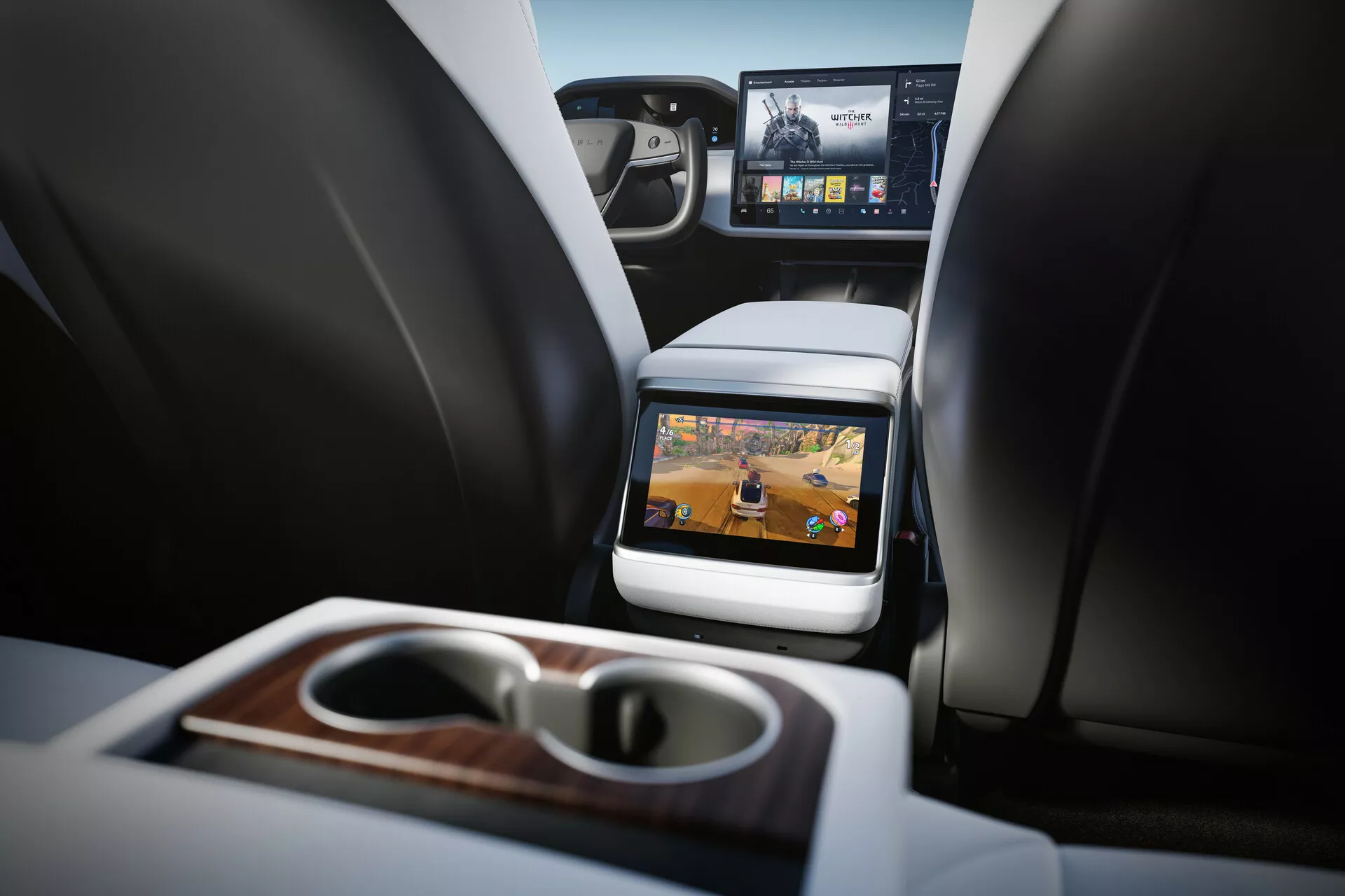 Interiérový pohľad na Tesla Model S 2016 (prvá generácia facelift) so zameraním na priestory pre cestujúcich vzadu. Perspektíva z výšky sedadla vzadu, vidiache dve predné sedadlá s opierkami hlavy, stredovú konzolu a zabudovanú obrazovku na zadnej strane sedadla spolujazdca. Technológia zábavy pre zadné sedadlá so zjavnou aktívnou obrazovkou zobrazujúcou multimediálny obsah. Funkcie zahŕňajú sklápacie opierky na ruky s integrovanými držiakmi na poháre a dreveným prevedením, čiastočný výhľad na prednú palubnú dosku s väčšou infotainmentovou obrazovkou a luxusné materiály. Dobre osvetlený interiér s neutrálnymi tónmi naznačuje moderné luxusné vozidlo.
