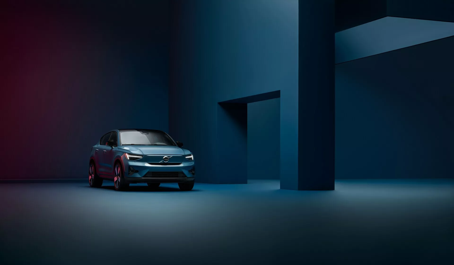 Profesionálna fotografia vozidla Volvo C40 z roku 2021 (1. generácia) z predného trojštvrťového pohľadu, zvýrazňujúca modernú mriežku, LED svetlomety a elegantný bočný profil v tlmene osvetlenom, atmosférickom ateliéri.