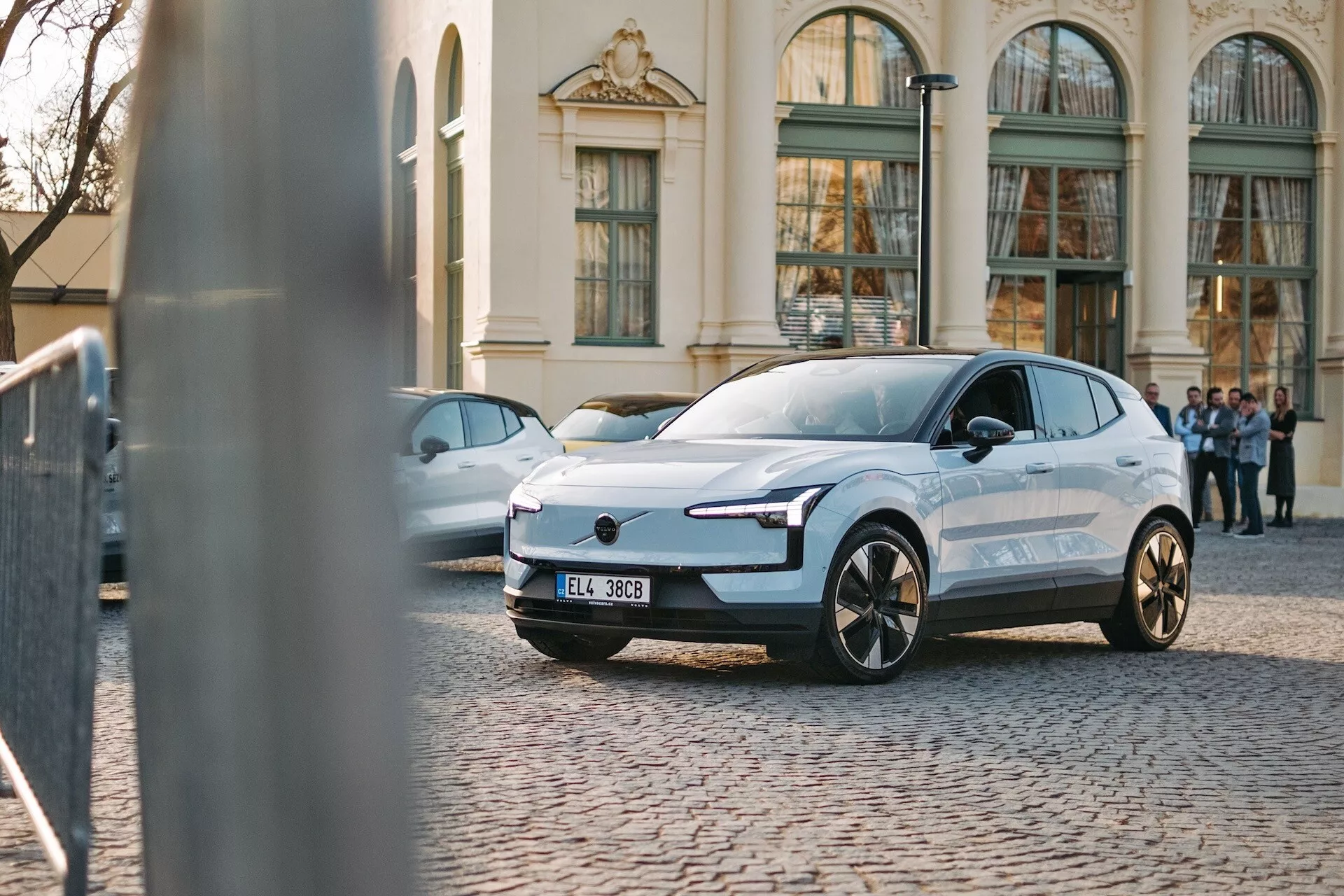 Elektrické SUV Volvo EX30 z roku 2024 zaparkované na dlažobných kockách, ukazuje trojštvrtečný predný pohľad, vyznačuje sa štýlovým dizajnom, úzkymi LED svetlometmi a aerodynamickými obrysmi