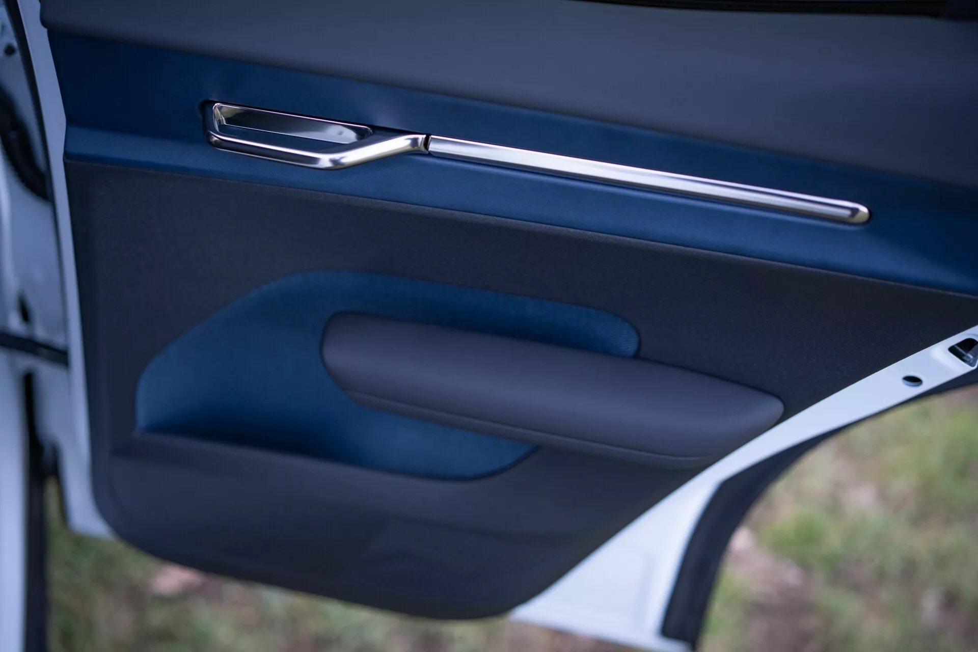 Detailný pohľad na interiér dverí vozidla Volvo EX30 2024, ukazujúci štýlovú kovovú kľučku dverí, ergonomickú opierku ruky a úložný priestor v tmavom prevedení vysokej kvality