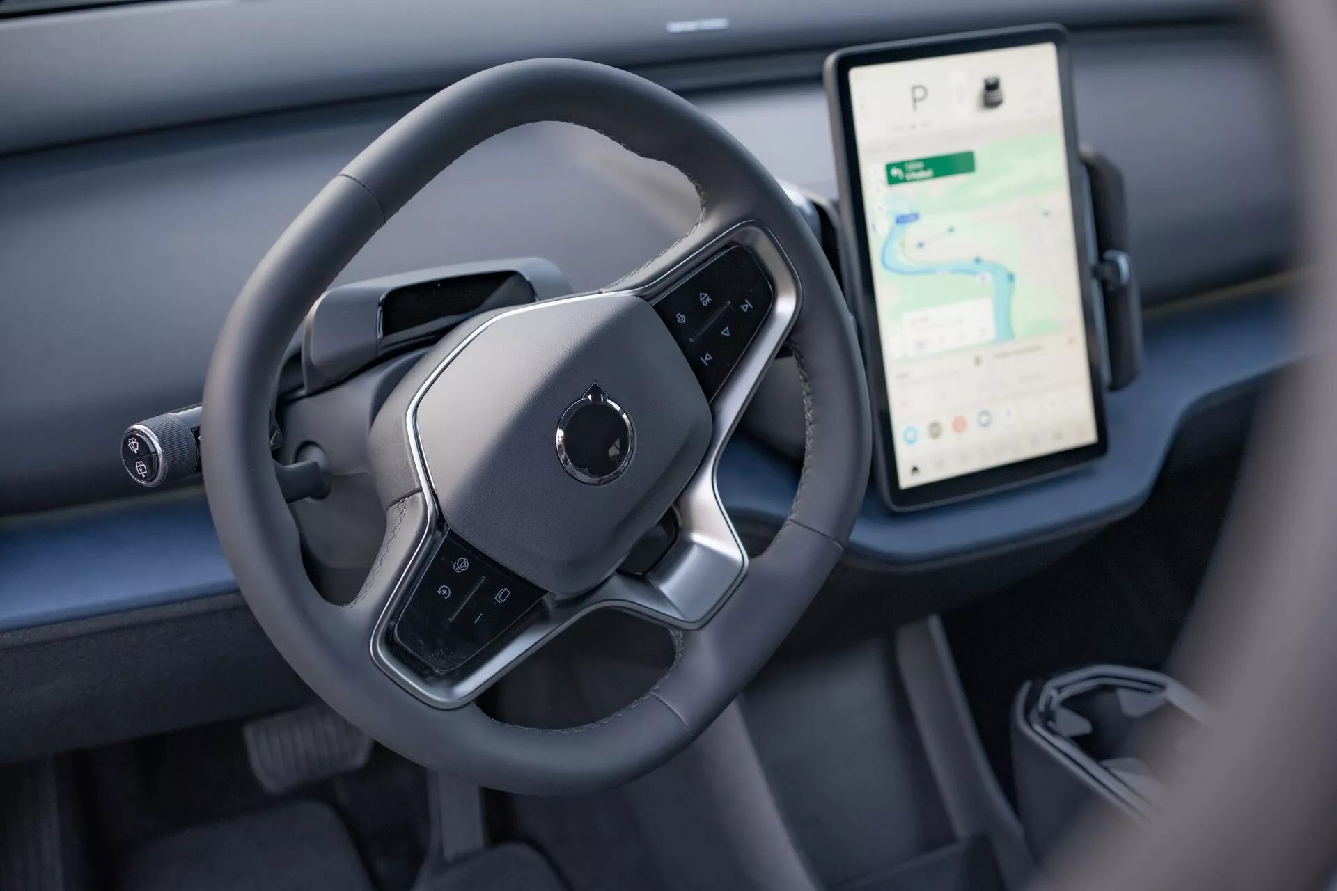 Interiér Volvo EX30 2024 so zameraním na oblasť ovládania vodiča s moderným volantom s plochým dnom a veľkým vertikálnym dotykovým displejom pre navigáciu a médiá na prístrojovej doske
