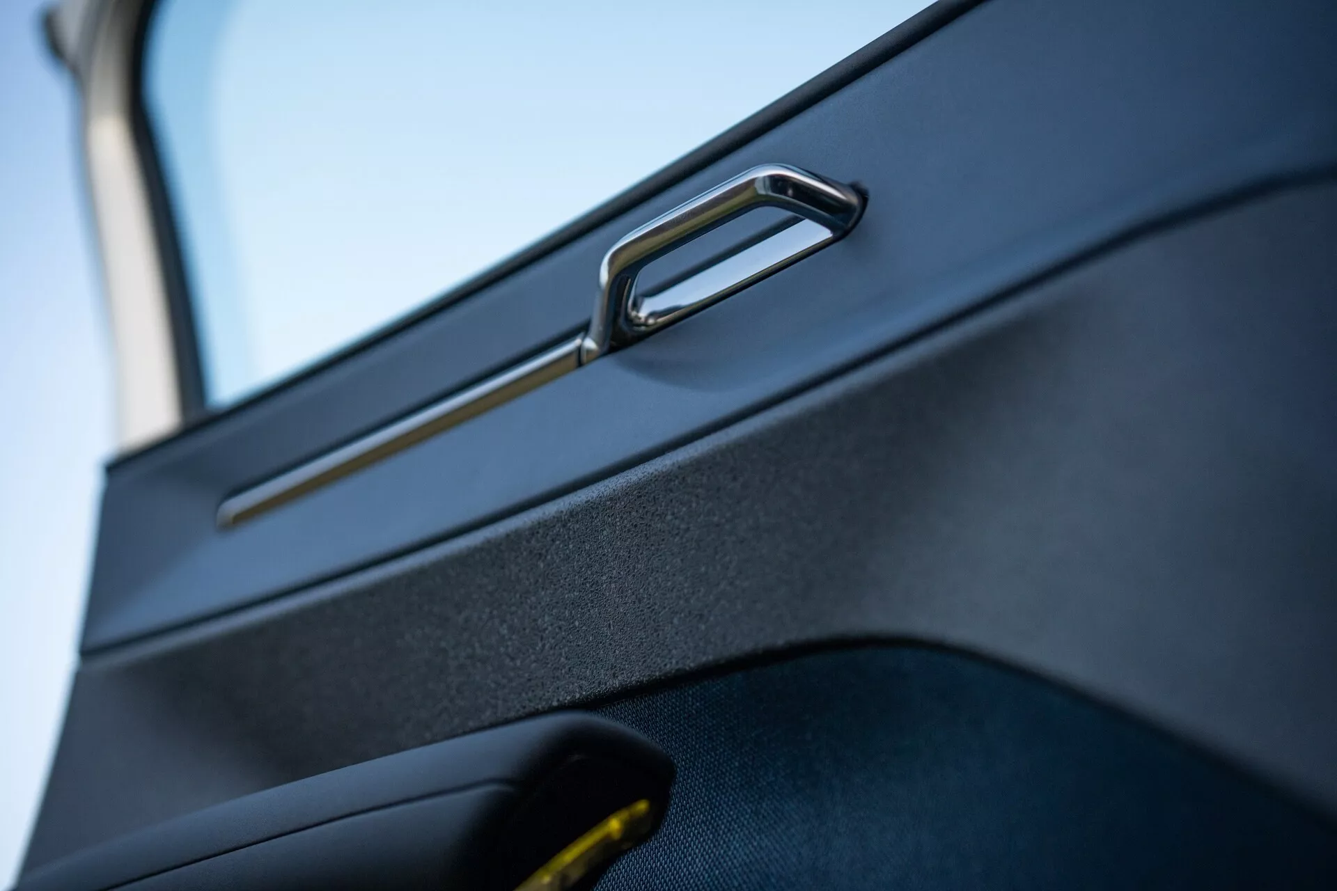 Detailný pohľad na dverový panel Volvo EX30 2024 s chrómovou kľučkou a úložným priestorom, ktorý zvýrazňuje moderný, ergonomický dizajn a textúrovaný povrch materiálu od Volvo.