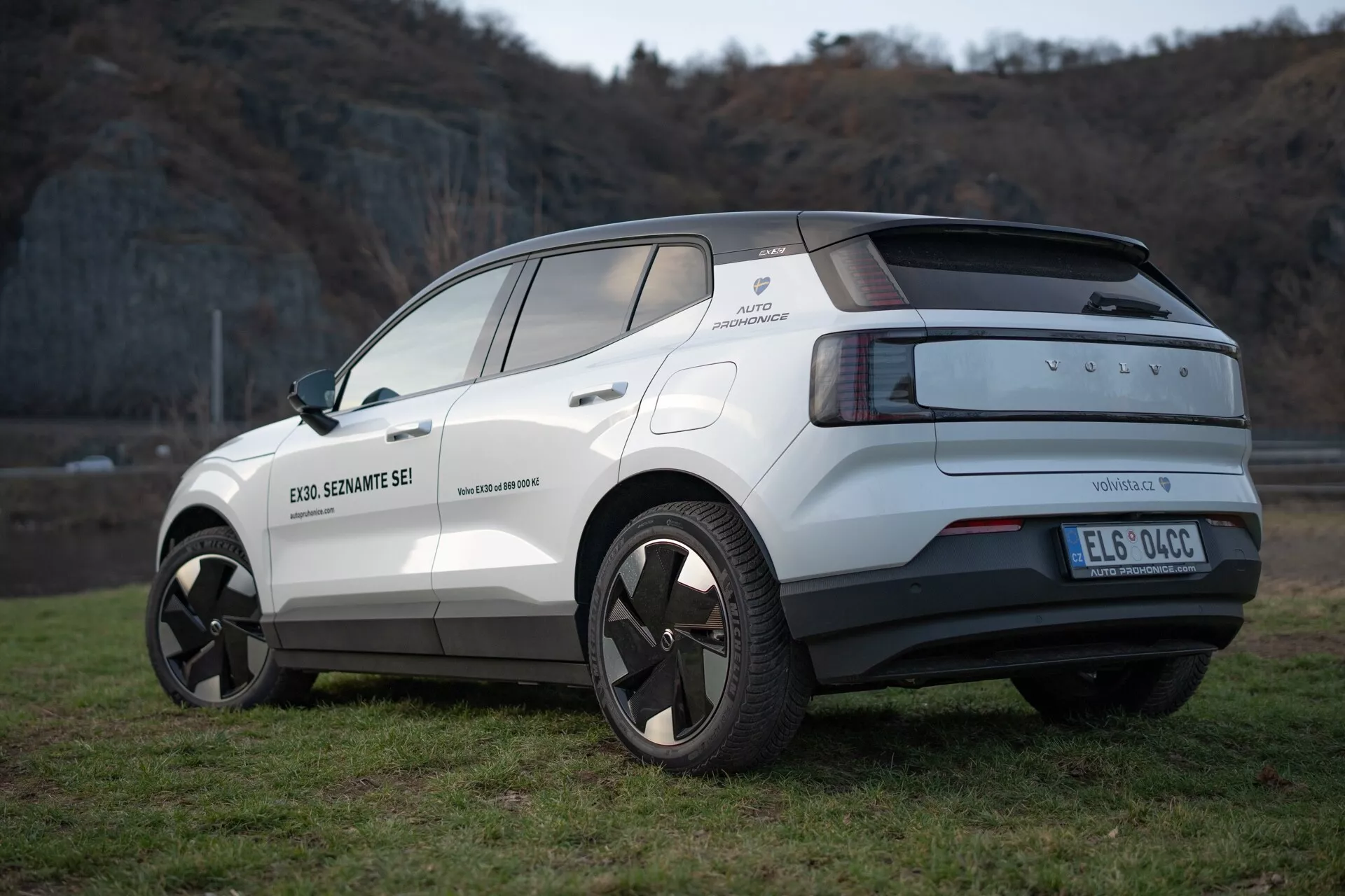Zadný trojštvrtečný pohľad na elektrický crossover Volvo EX30 ročník 2024 v bielej farbe, ktorý zdôrazňuje jeho moderný dizajn, zliatinové disky, parkovacie senzory a funkcie asistencie vodiča