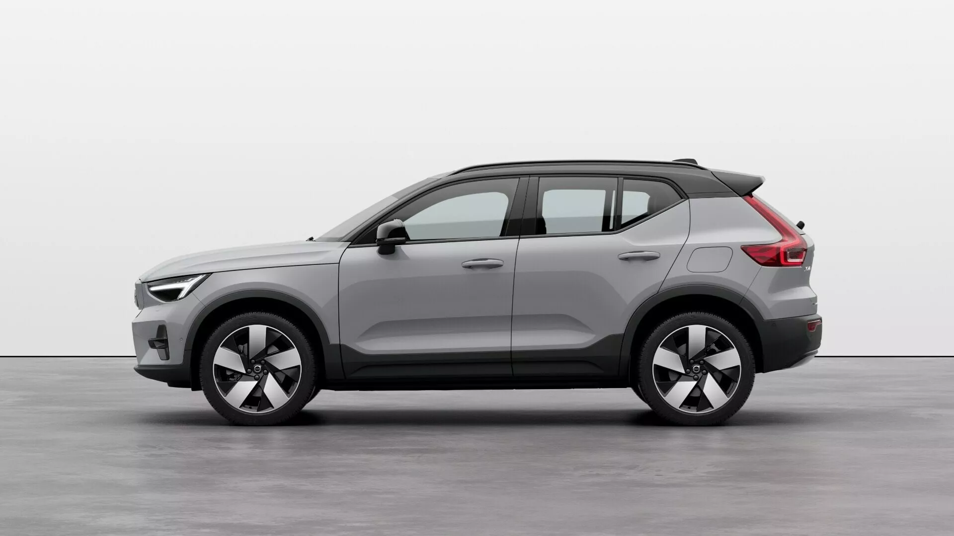 Volvo EX40 1. generácia 2024 v štúdiovom nastavení: Bočný profil ukazujúci celú dĺžku, kompaktný dizajn SUV, dvojfarebnú karosériu, veľké zliatinové kolesá, strešné nosiče a modernú estetiku