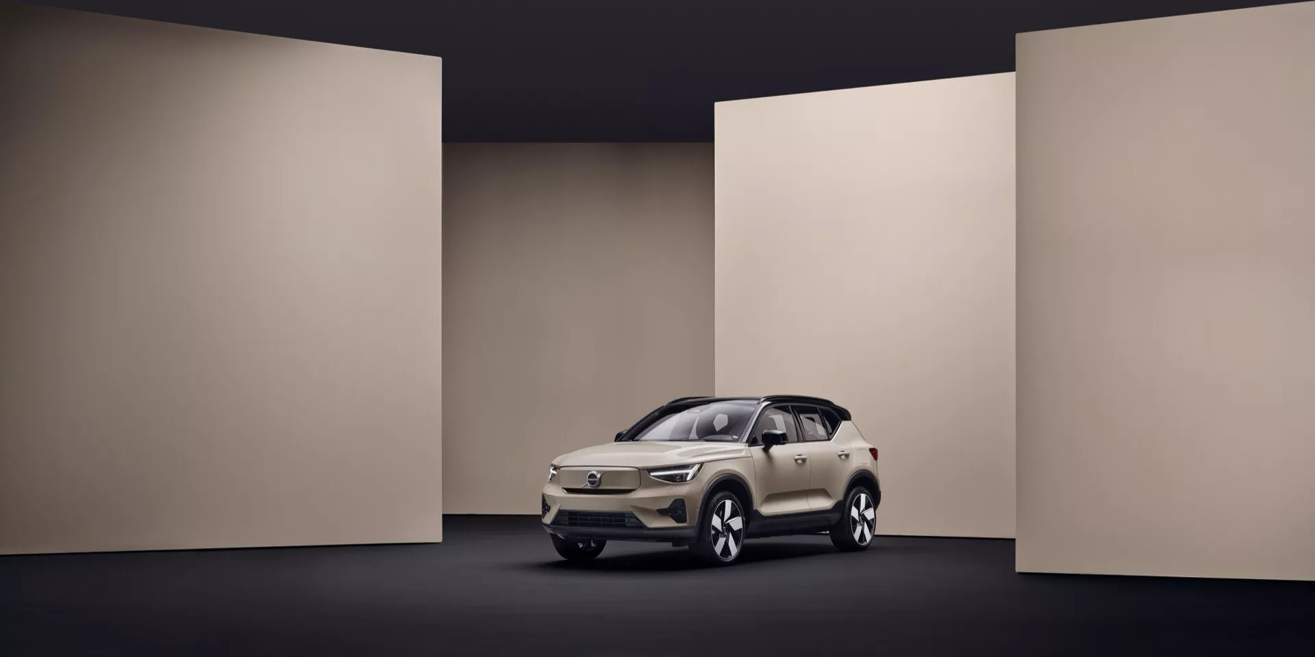 Volvo EX40 2024 1. generácia v krémovej farbe predstavené v štúdiu s kontrolovaným osvetlením, zdôrazňujúce jeho elegantný dizajn, LED svetlomety, výraznú mriežku a moderné technologické funkcie