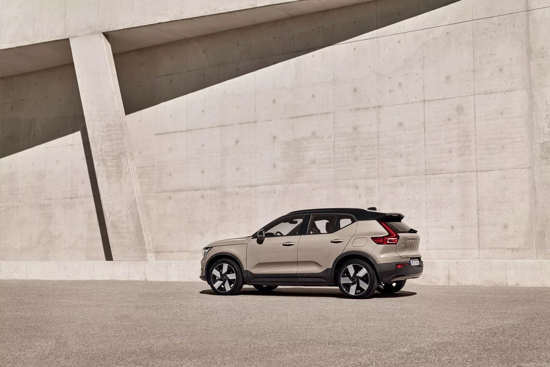 Model Volvo EX40 1. generácie z roku 2024 zaparkovaný s elegantným aerodynamickým dizajnom a dvojfarebným farebným schémou s veľkými zliatinovými kolesami, oknami s ochranou súkromia a modernými LED zadnými svetlami v minimalistickom mestskom prostredí