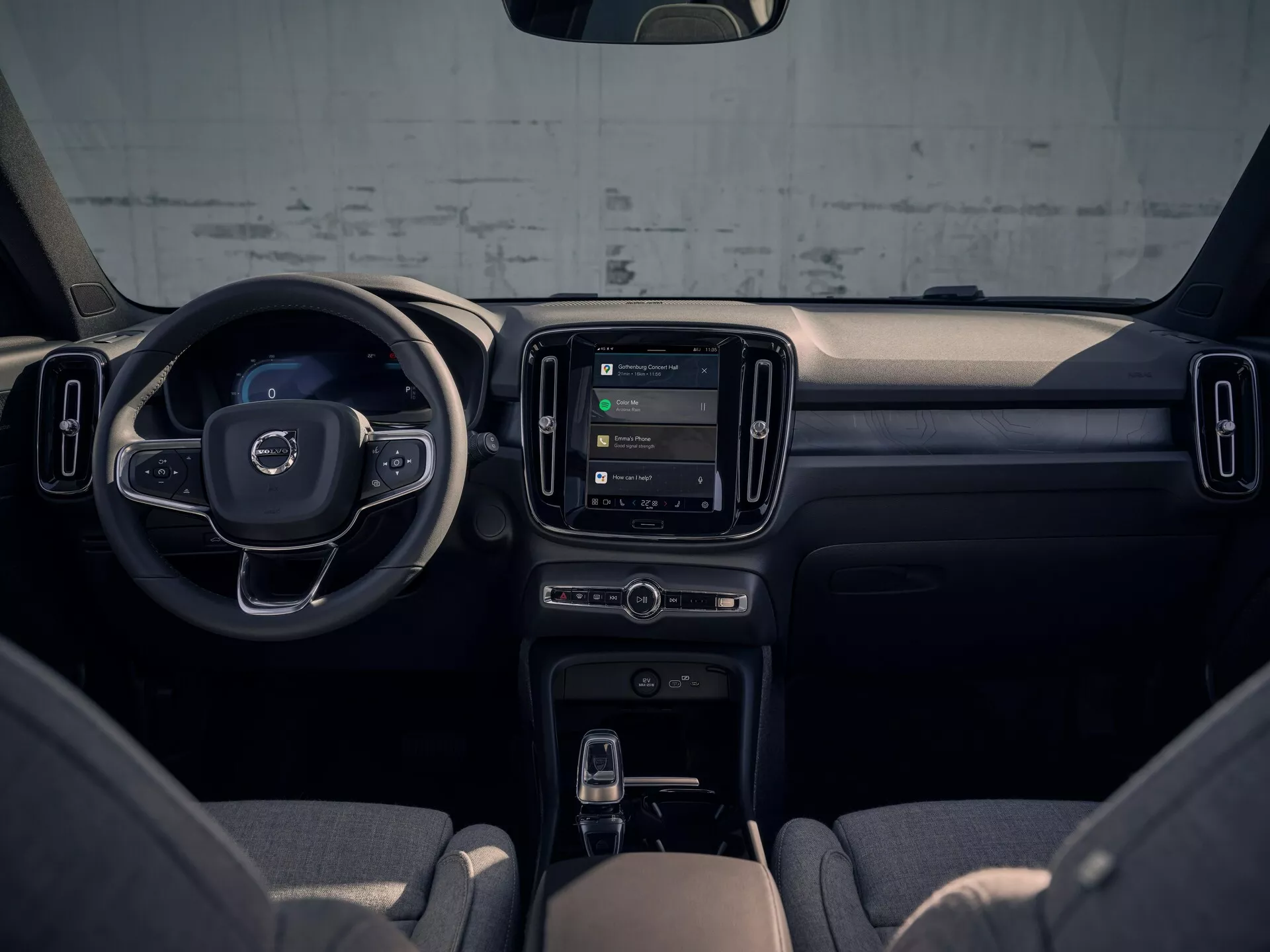 Pohľad na interiér Volvo EX40 2024, ktorý zdôrazňuje prístrojovú dosku, stredovú konzolu a volant z pohľadu zadného pasažiera, predvádzajúci moderný dizajn a technologické funkcie