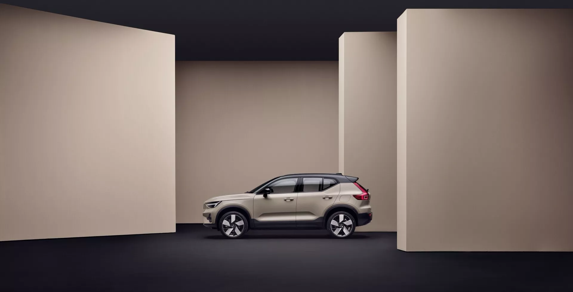 Volvo EX40 1. generácia 2024 zobrazené v plnom profilovom pohľade na tmavom pozadí, zdôrazňuje bočné dizajnové prvky vozidla, aerodynamickú karosériu a pokročilé funkcie, ako sú ľahké zliatinové kolesá a integrované smerové svetlá