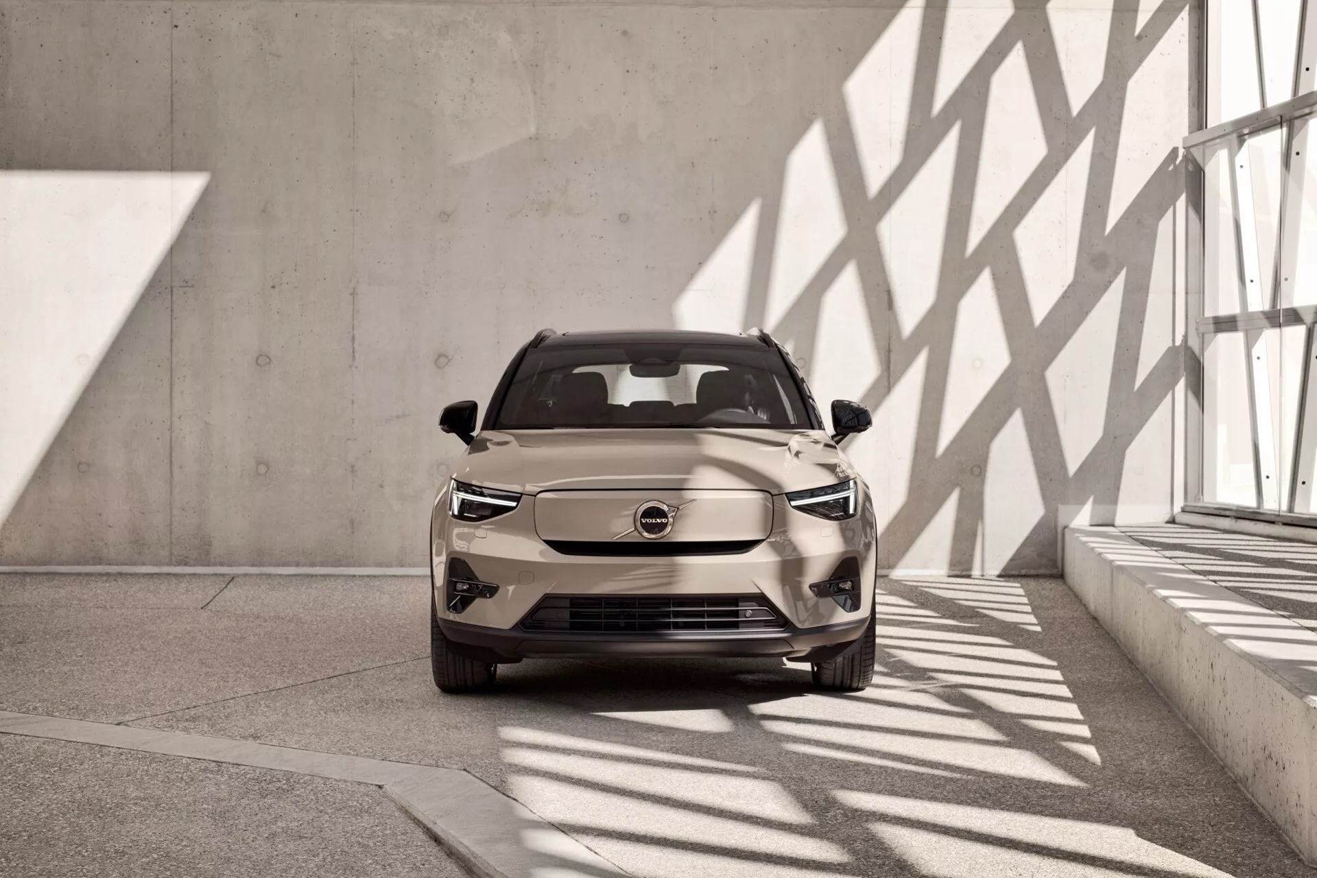 Volvo EX40 z roku 2024, 1. generácia, zobrazené z mierne skosené čelnej perspektívy vo vnútri showroomu vo svetle neutrálnom odtieni, s LED svetlometmi a moderným aerodynamickým dizajnom, naznačujúcim črty elektrického vozidla
