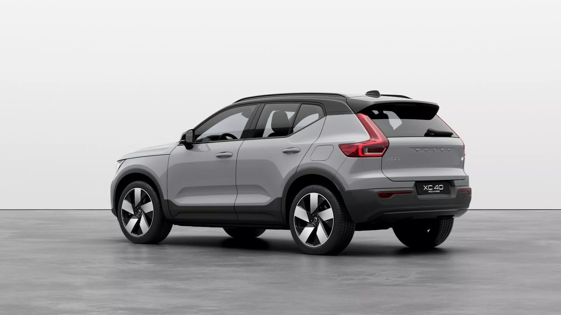 Volvo EX40 prvej generácie 2024 vo výhľade z troch štvrtín zadnej strany, ktorý prezentuje jeho kompaktnú až stredne veľkú SUV karosériu, športovo sklonenú zadnú strechu, integrované zadné krídlo, LED zadné svetlá s moderným svetelným podpisom, dvojité výfukové koncovky, viaceré hovorové zliatinové kolesá a bočné zrkadlá s integrovanými smerovými svetlami v štúdiovom prostredí.