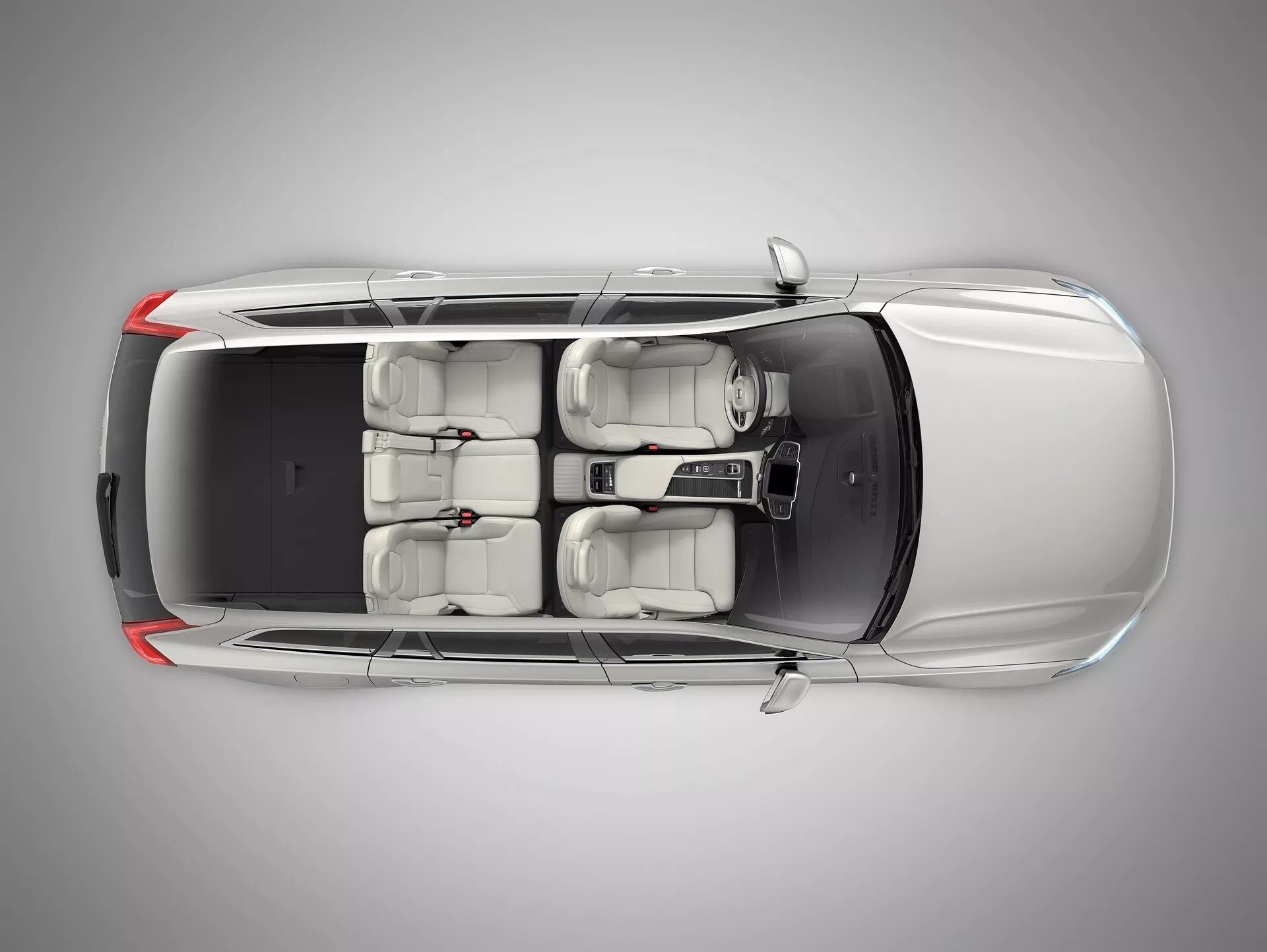 Pohľad z vtáčej perspektívy na Volvo XC90 2015 (2. generácia), ktorý zobrazuje prémiový sedan zhora. Uhol poskytuje jasný výhľad na strechu, kapotu, kufor a povrchy dverí. Vlastnosti zahŕňajú dvojpanelové strešné okno nad prednými sedadlami, interiér svetlej farby s kapacitou pre päť cestujúcich, zliatinové kolesá a viditeľné bočné zrkadlá. Zadné okno je strmo sklonené a žiadne konkrétne značky nie sú viditeľné.