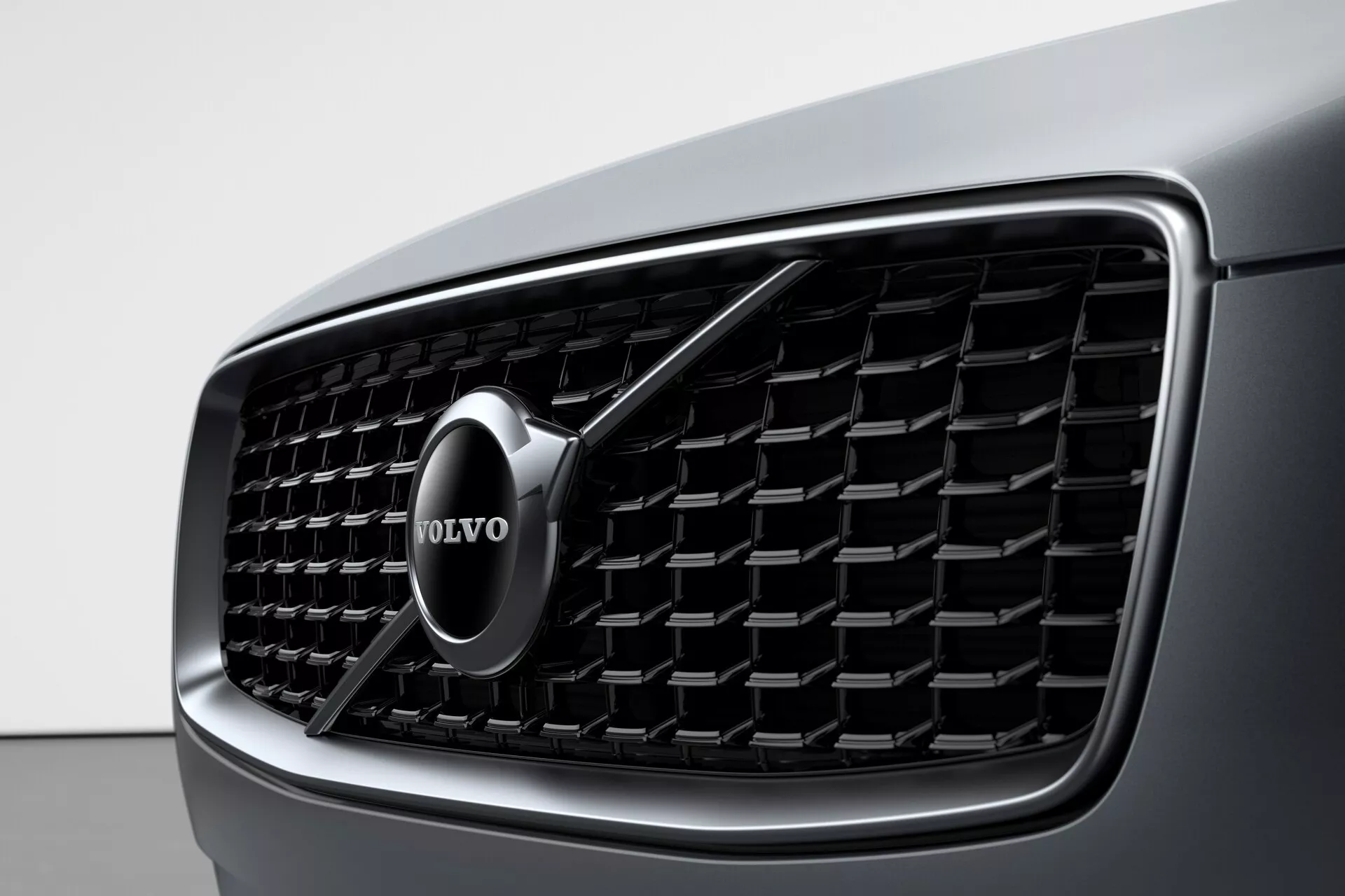 Detailný pohľad na prednú masku vozidla Volvo XC90 2015 (2. generácia), s dôrazom na detailný dizajn a výrazný znak značky Volvo. Maska má vertikálne lamely a chrómový obrys, čo zdôrazňuje luxus a modernú estetiku.