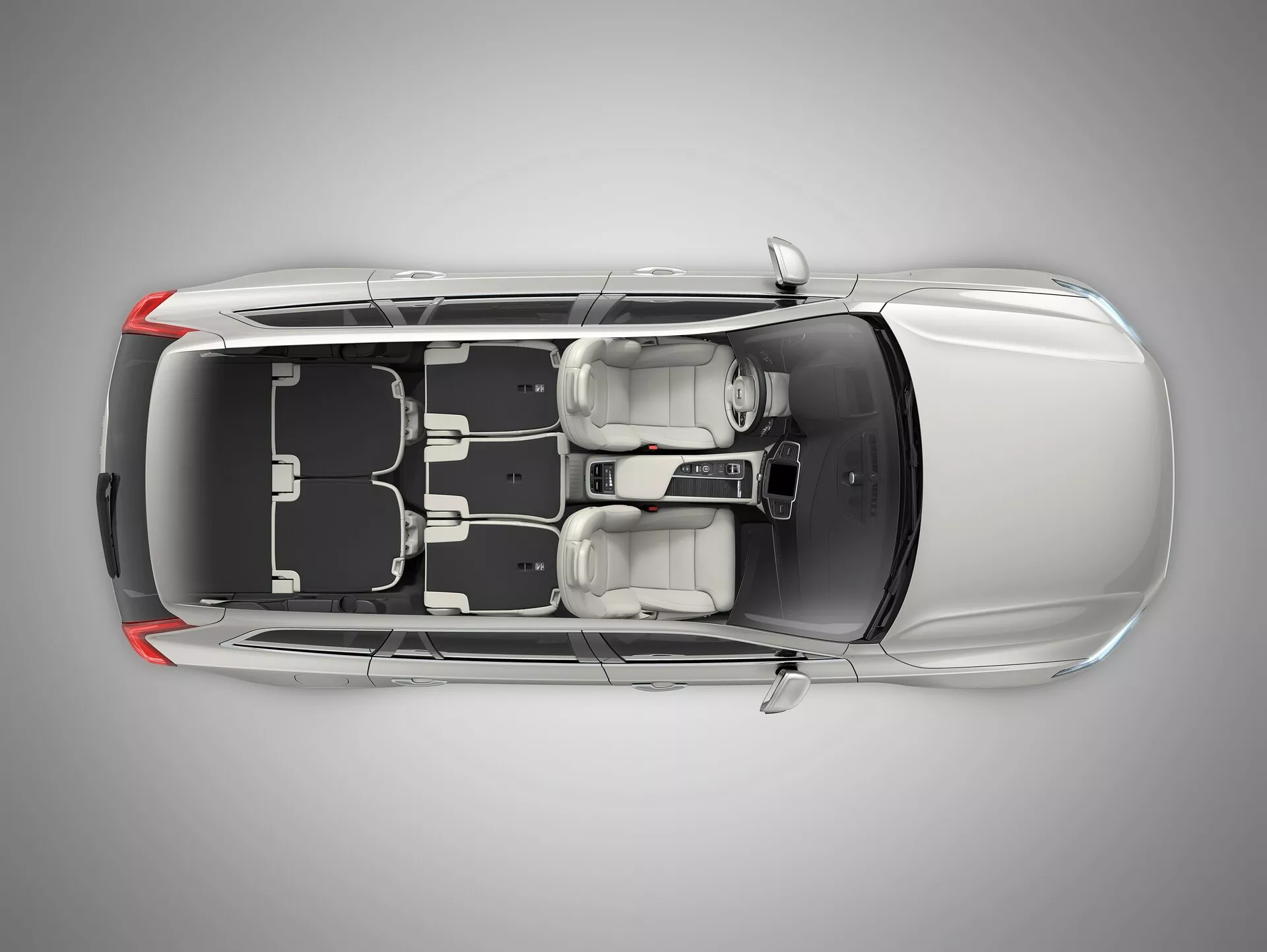 Pohľad z vtáčej perspektívy na Volvo XC90 z roku 2015 druhej generácie, zobrazujúci čiernu strechu a kovovo strieborné alebo sivé karosérie so strešným oknom, zatvorenými dverami a oknami. Jasne viditeľné sú kolesá a dizajn ráfikov, ako aj bočné zrkadlá, čo zdôrazňuje bezpečnosť a vonkajšie vlastnosti. Zúžená línia strechy pri zadnej časti naznačuje, že by to mohol byť štvordverový sedan alebo kupé.