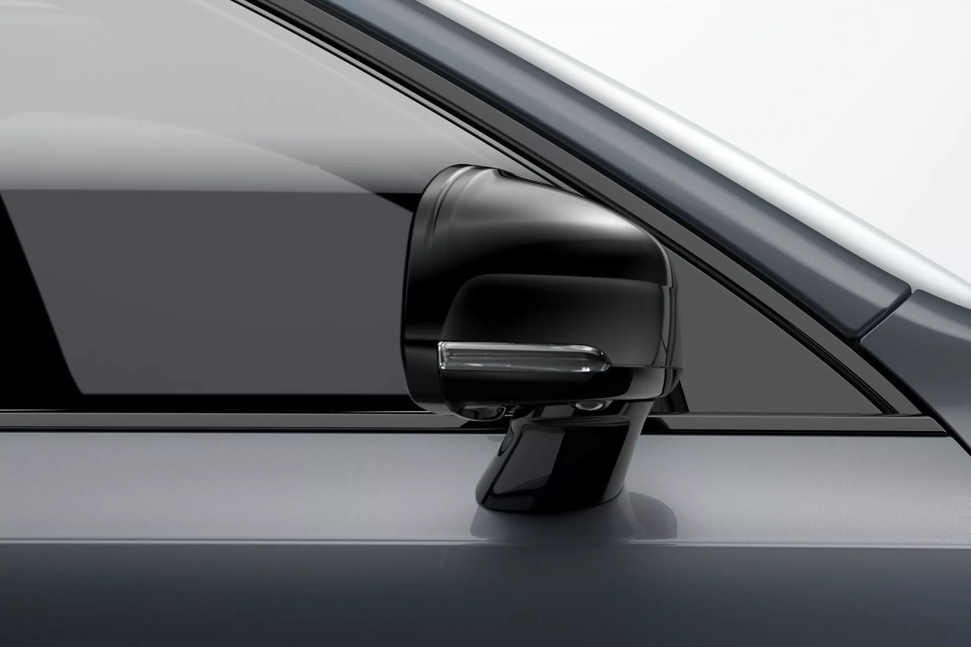 Detailný pohľad na zostavu spätného zrkadla na strane vodiča na vozidle Volvo XC90 2015 (2. generácia). Obrázok zvýrazňuje moderný aerodynamický dizajn s integrovaným smerovým svetlom, potenciálne súčasťou pokročilého asistenčného systému vodiča, a farebne zladené puzdro. Vidíme čiastočný pohľad na A-stĺpik, bočné okno a dverový panel. Fotografia je nasnímaná z mierne predného uhla, ukazujúc prémiový monochromatický vzhľad vozidla.