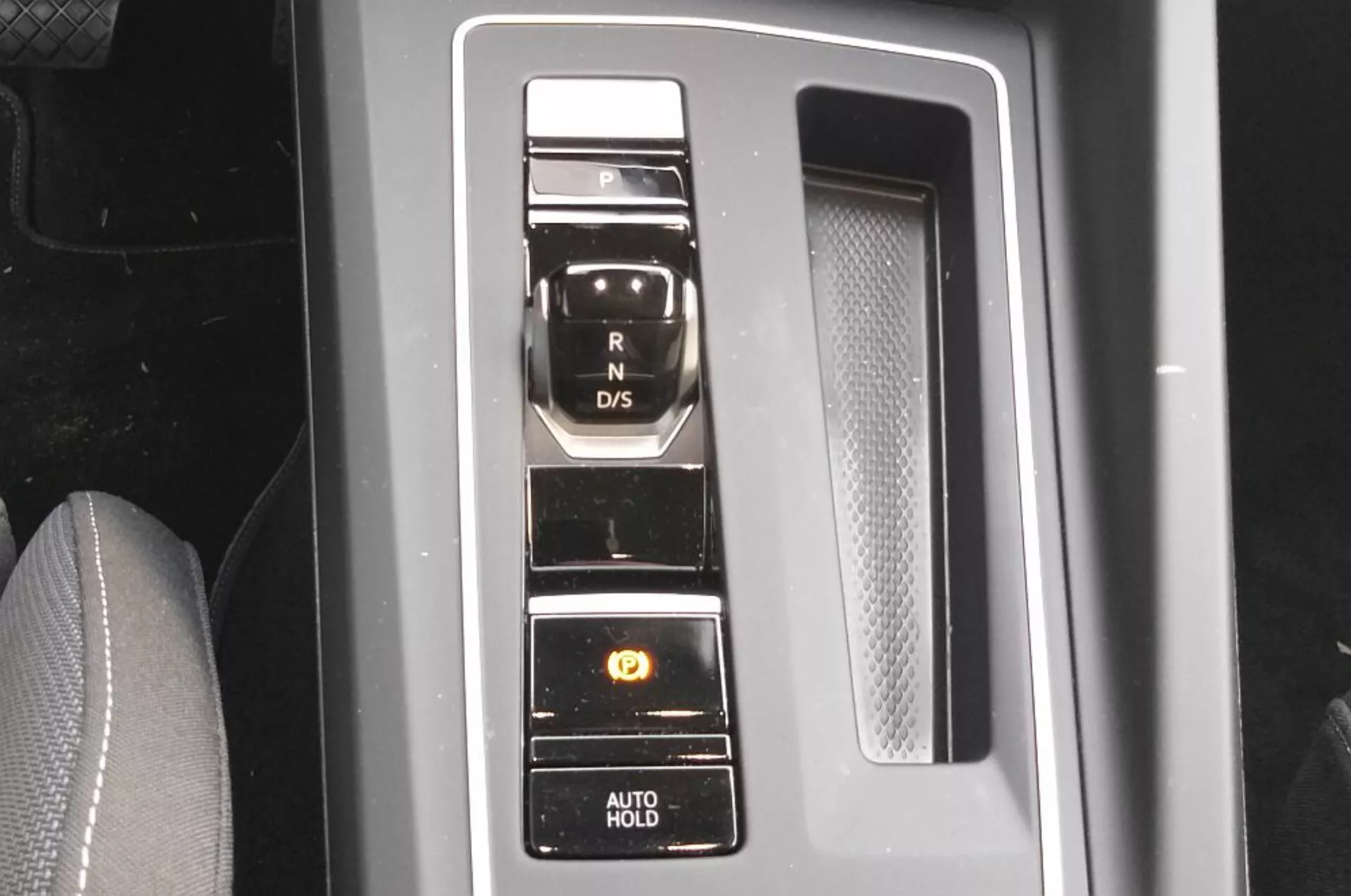 Zbližný pohľad na elektronický výberový mechanizmus prevodovky VW Golf GTD 2017 s vertikálnym usporiadaním tlačidiel na pianovom čiernom paneli s chrómovými akcentmi, predvádzajúci modernú technológiu prenosového systému a pohodlné funkcie ako je parkovacia brzda a funkcia AUTO HOLD
