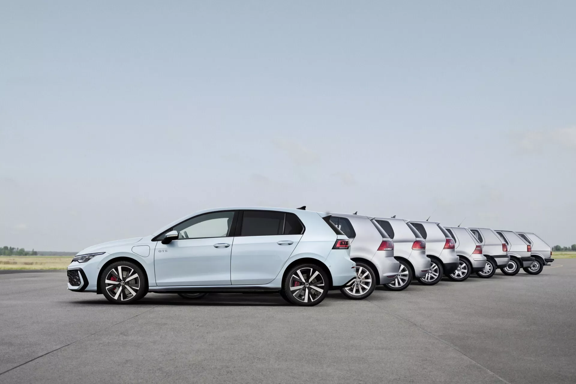 VW Golf Hatchback 2024 (VIII-Facelift) v pevnej bielej farbe, zobrazujúci pohyb prostredníctvom efektu časozberu na vzletovej dráhe, s karosériou hatchback, zliatinovými kolesami, integrovanými smerovkami v spätných zrkadlách v farbe karosérie a kontrastnou čiernou strechou.