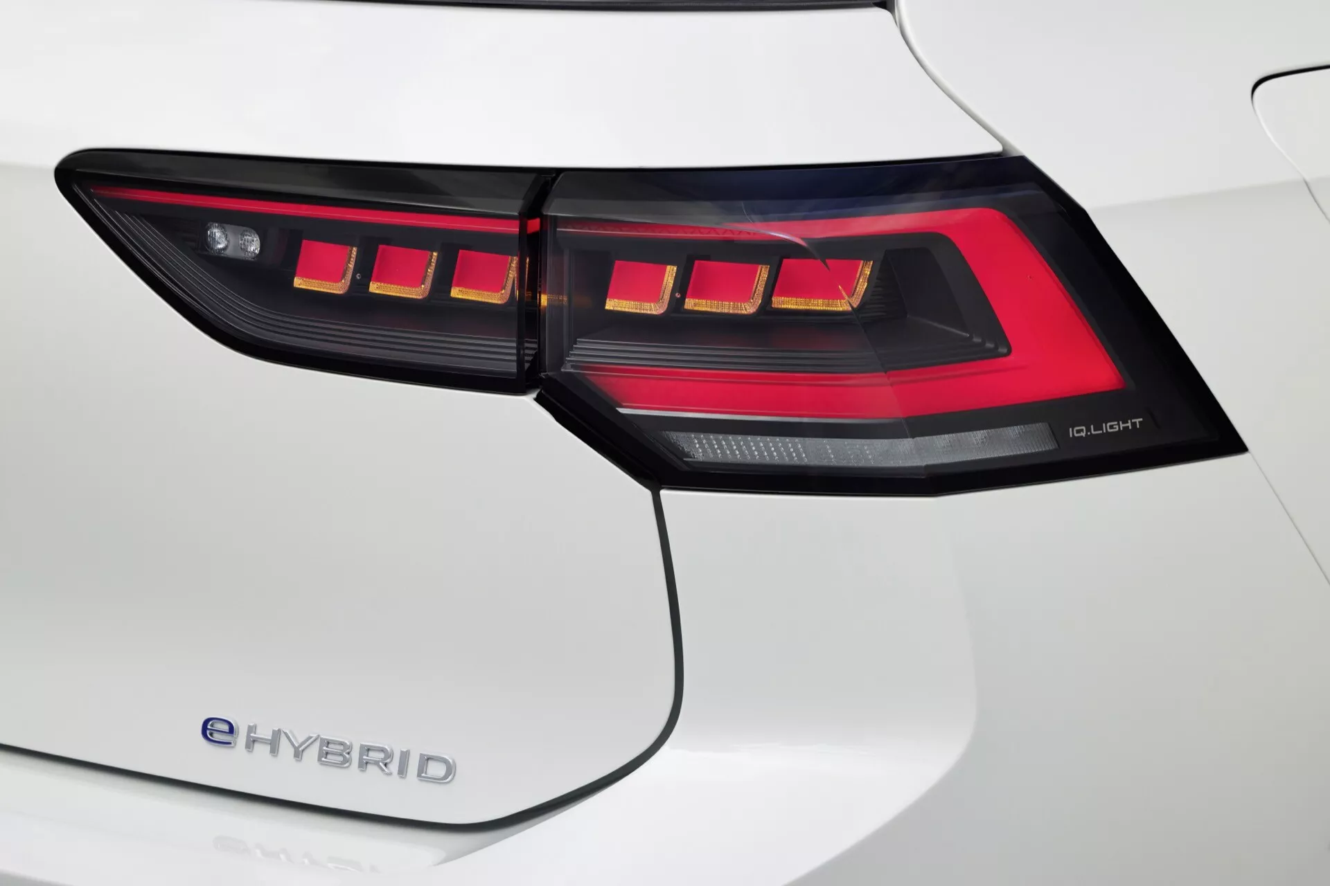 Detailný pohľad na pravé zadné svetlo VW Golf 2024 (VIII facelift) e-HYBRID s technológiou OLED a výrazným vzorom LED, doplnené o biely zadný diel blatníka.
