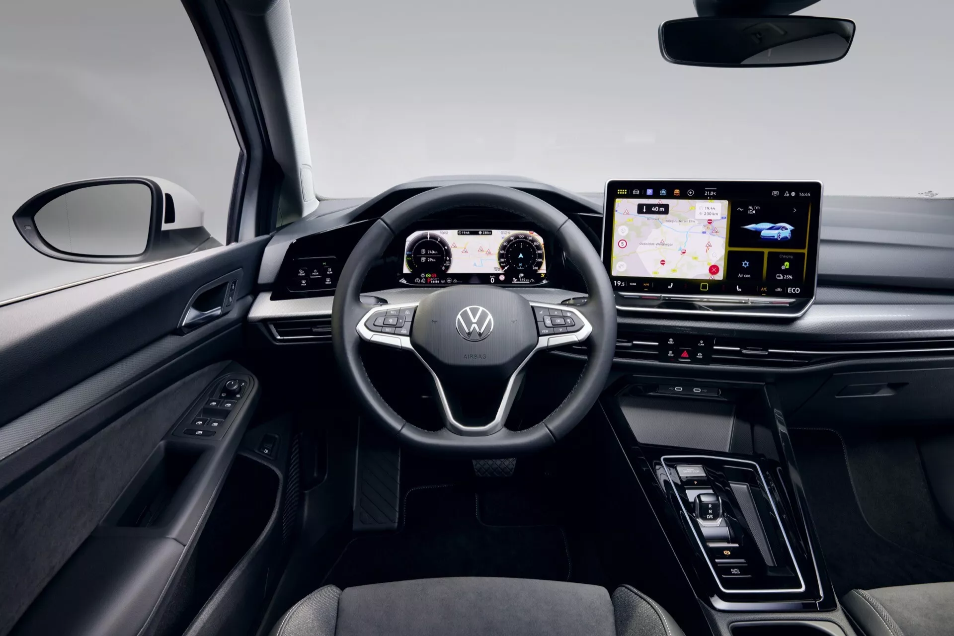 Interiér VW Golf VIII-Facelift 2024 s výhľadom na palubnú dosku vodiča, digitálny prístrojový panel a širokouhlý informačný systém z perspektívy zadného pasažiera