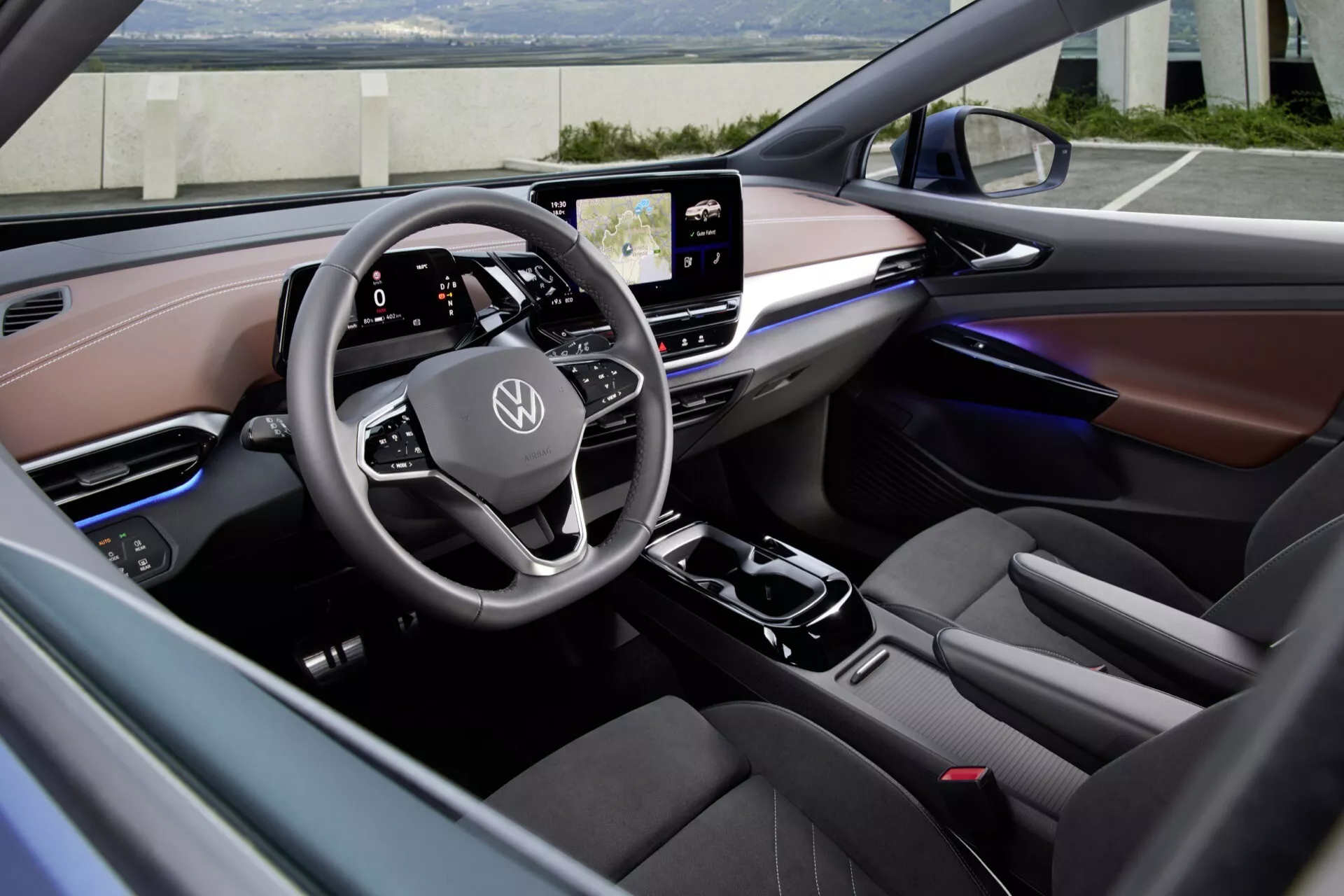Pohľad na interiér VW ID.5 2022 1. generácie z predného sedadla spolujazdca, zvýrazňujúci multifunkčný volant s dotykovým ovládaním, integrovaný digitálny prístrojový panel, centrálny dotykový infotainment systém, modernú stredovú konzolu s radiacou pákou, ambientné osvetlenie, prémiové materiály, ergonomické vodičovo sedadlo, štandardné bezpečnostné prvky a elegantný panel klimatizácie.