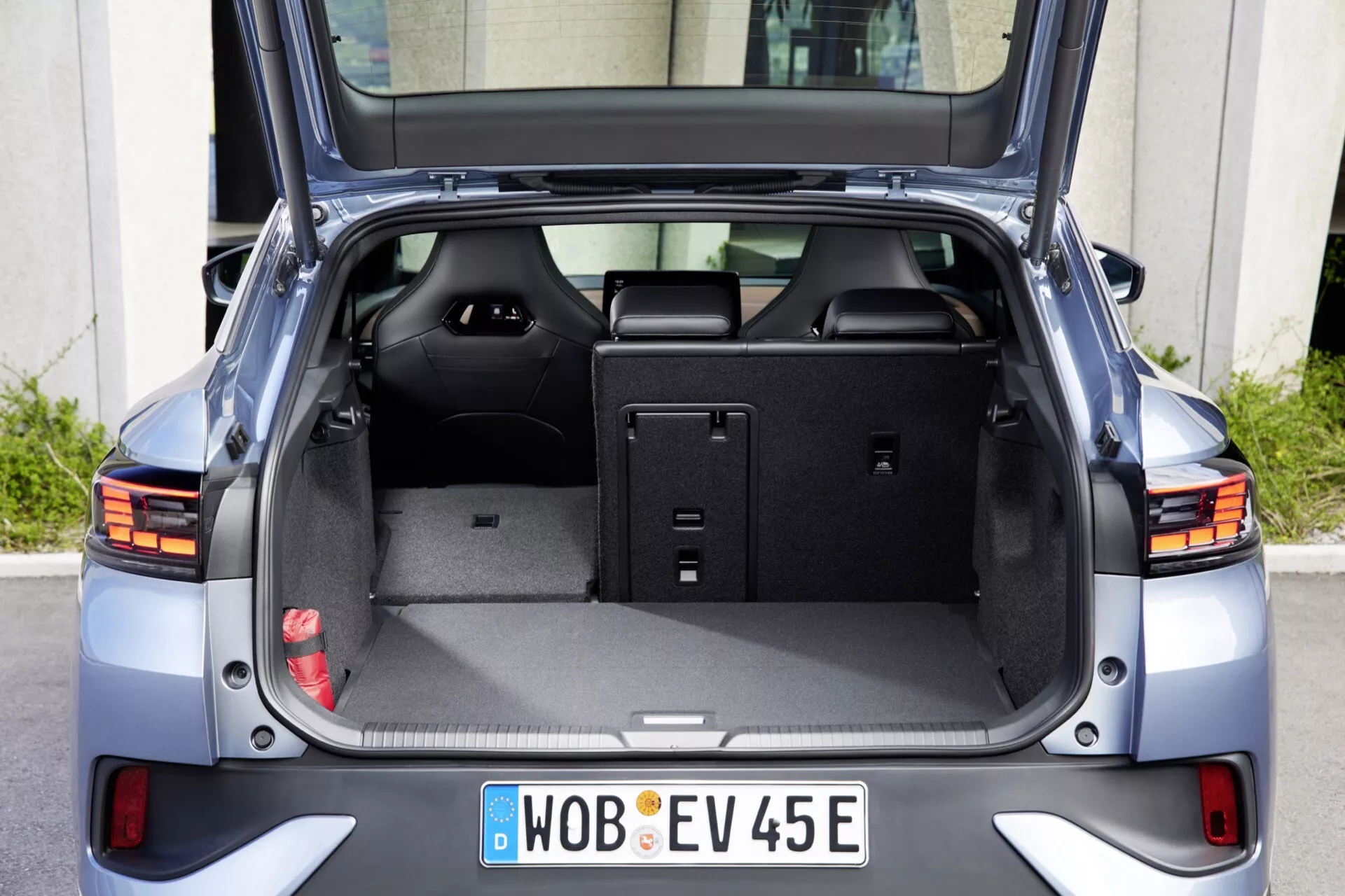 Zadný pohľad na VW ID.5 2022 prvej generácie s otvoreným zadným vekom batožinového priestoru, odhaľujúcim priestrannú nakladaciu plochu s plochou podlahou a sklopenými zadnými sedadlami. Obrázok zdôrazňuje zväčšenú kapacitu batožinového priestoru, moderné zadné LED svetlá a označenie elektrického vozidla na centrálne umiestnenej registračnej značke. Medzi ďalšie funkcie patrí zasúvací kryt batožinového priestoru, vnútorné úložné priestory a chrómové ozdobné prvky.
