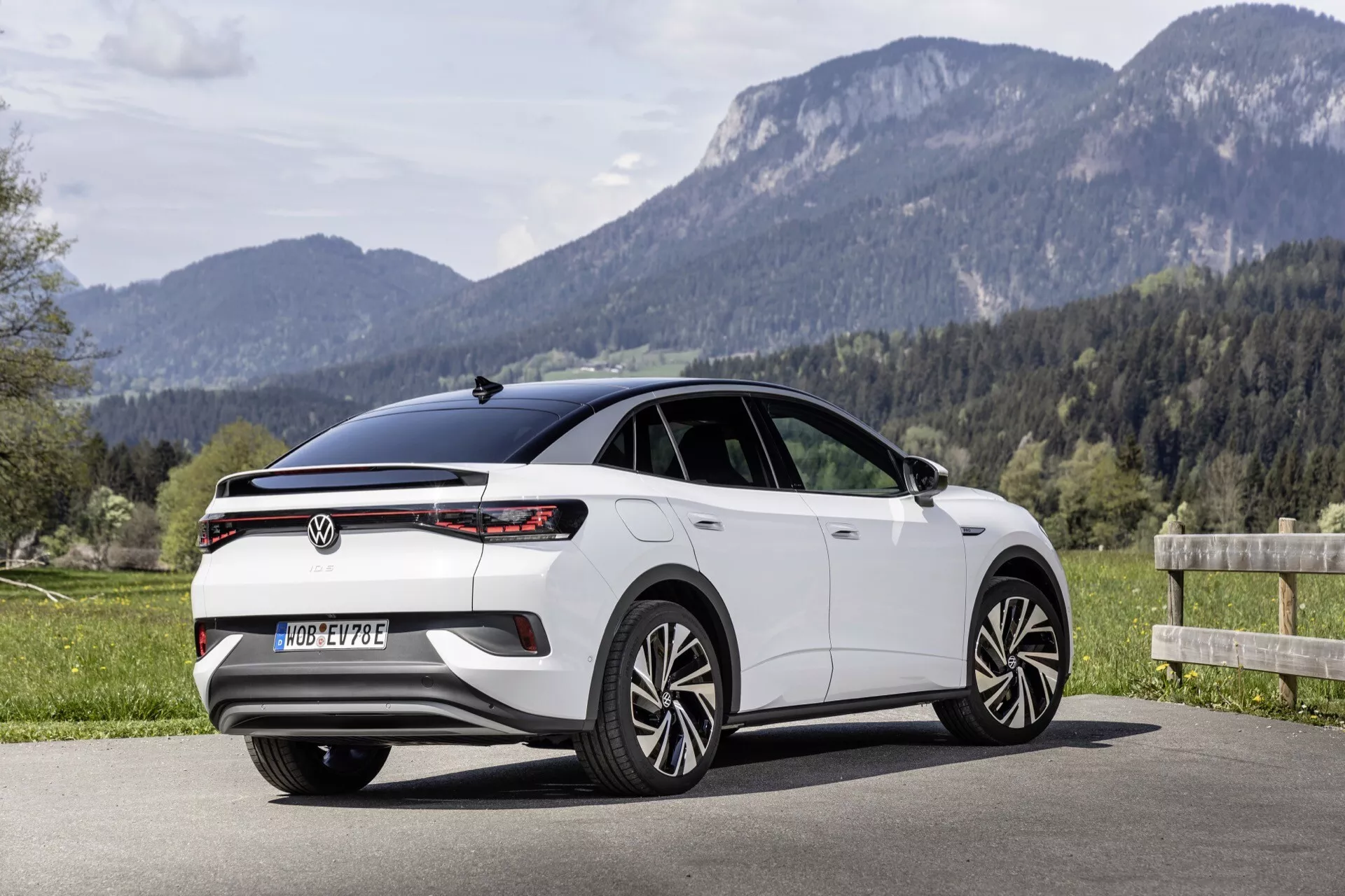 Bočný a zadný trojštvrťový pohľad na hatchback VW ID.5 z roku 2022 (1. generácia), ktorý ukazuje moderný dizajn s horizontálnymi LED zadnými svetlami, plnošírkovým svetelným pruhom, vysoko umiestneným brzdovým svetlom integrovaným do zadného spojlera, elegantnými líniami okien, zapustenými kľučkami dverí, viacerými ramenami diskov a panoramatickou strechou. Automobil je odfotený vonku v prírodnom prostredí v pozadí, čo naznačuje všestrannosť v rôznych jazdných podmienkach.