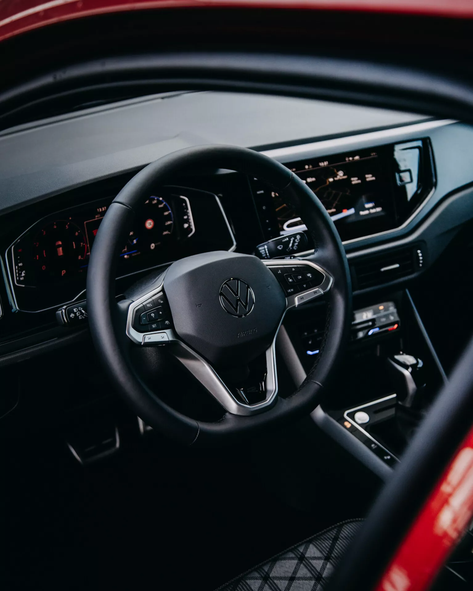 Pohľad do interiéru Volkswagen Taigo 2021 so zameraním na volant s ovládacími prvkami, digitálny palubovku a centrálnu infotainment konzolu z pohľadu zadného cestujúceho