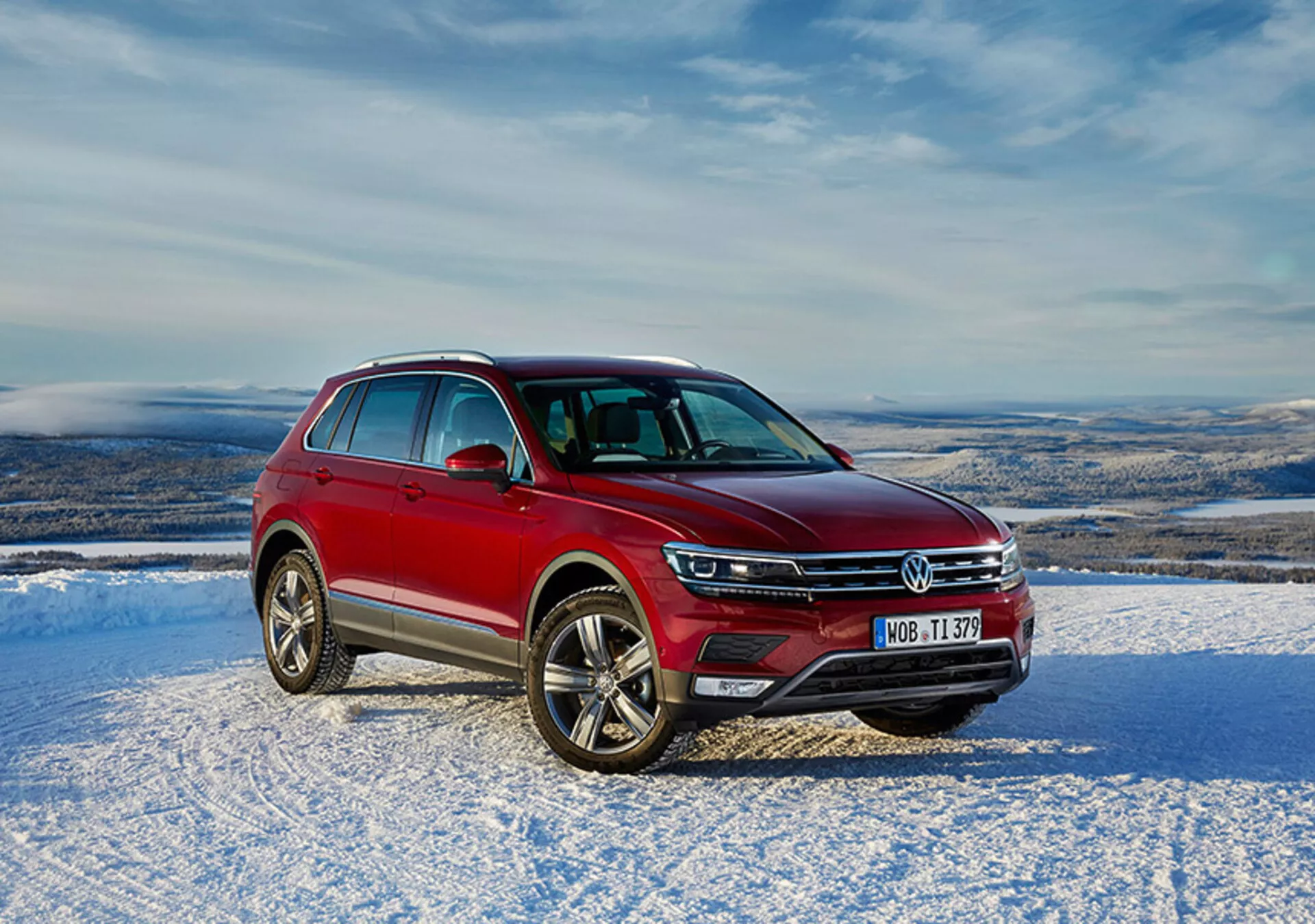 Červený Volkswagen Tiguan 2016 v snehovom vonkajšom prostredí s denným prírodným osvetlením, s prednou mriežkou, LED svetlometmi, chrómovými akcentmi a zliatinovými kolesami.