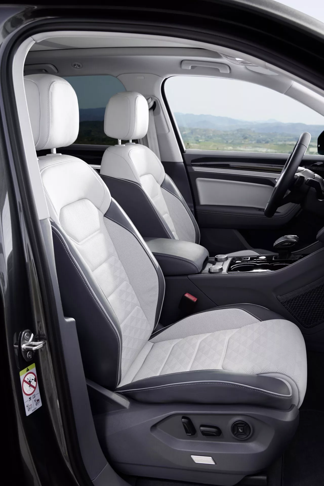Interiér Volkswagen Touareg III facelift 2023 s prednými sedadlami vo dvojfarebnom prevedení, dverami vodiča s ovládaním a okrajom prístrojovej dosky z mierne zvýšeného uhla