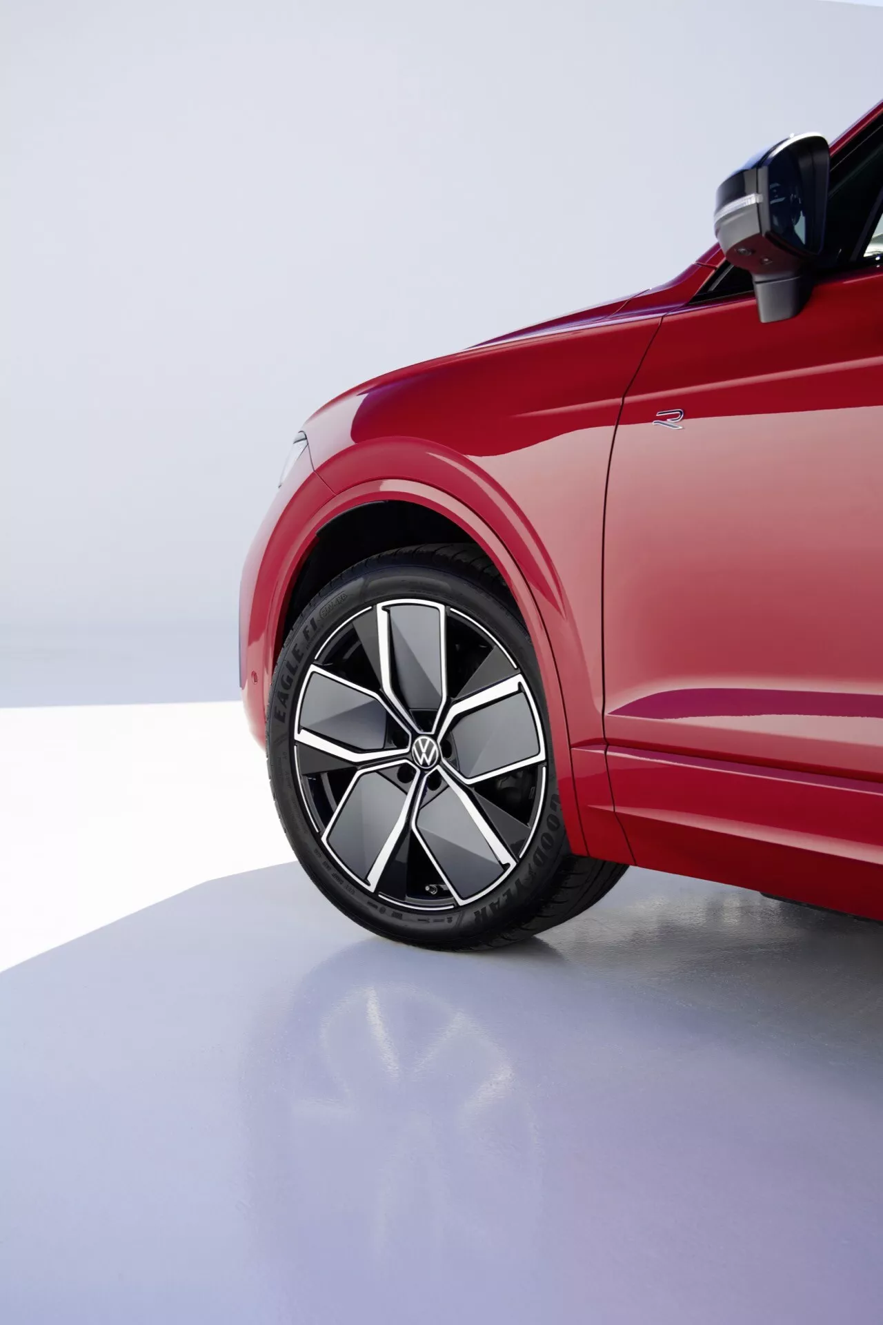Pohľad na prednú štvrtinu vodičovej strany VW Touareg Facelift 2023 zdôrazňujúci zliatinové koleso, nízkoprofilovú pneumatiku a dynamické línie karosérie pod profesionálnym štúdiovým osvetlením