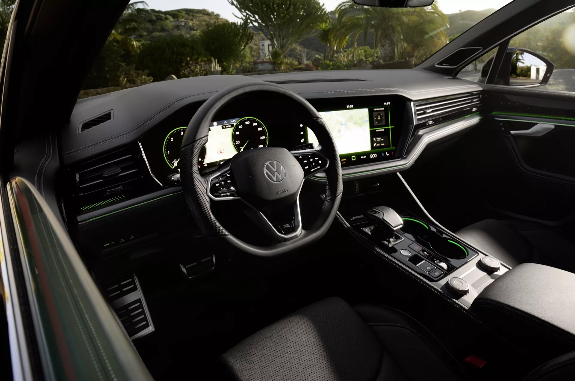 Interiér Volkswagen Touareg 2023 z pohľadu zo zadného sedadla ukazujúci palubnú dosku, digitálne displeje, volant s namontovanými ovládacími prvkami a stredovú konzolu v modernom a luxusnom dizajne