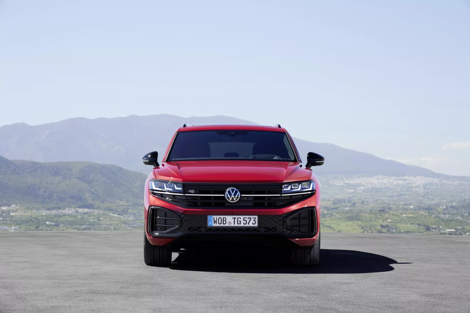 Predný pohľad na červený Volkswagen Touareg III facelift z roku 2023 s integrovanou mriežkou a skupinami LED svetlometov, ktoré zvýrazňujú dominanciu a moderné technologické vlastnosti vozidla