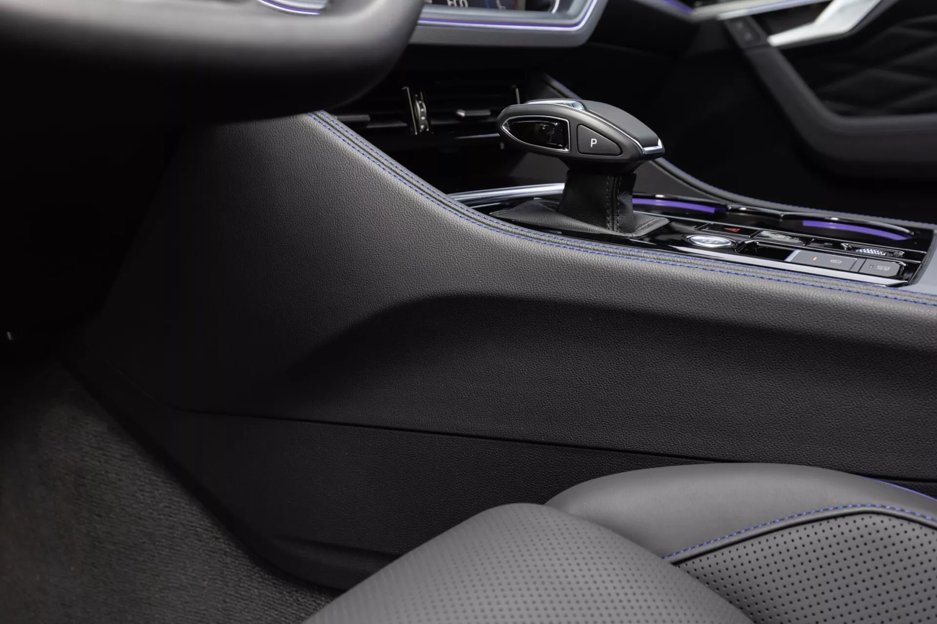 Detail interiéru Volkswagen Touareg 2023 s dôrazom na centrálnu konzolu, ergonomickú páku automatickej prevodovky a prémiové chrómové povrchy, zdôrazňujúci pokročilé ovládanie infotainmentu a klimatizované sedadlá