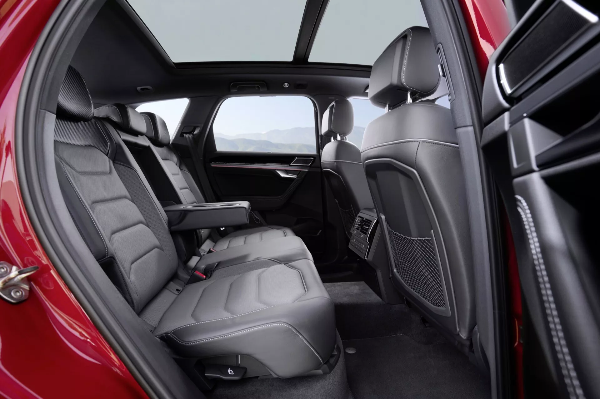 Interiér VW Touareg III po facelifte v roku 2023, ktorý zdôrazňuje luxusné kožené zadné sedadlá a pokročilé funkcie pohodlia pre cestujúcich, s prirodzeným osvetlením a dvojfarebnou farebnou schémou