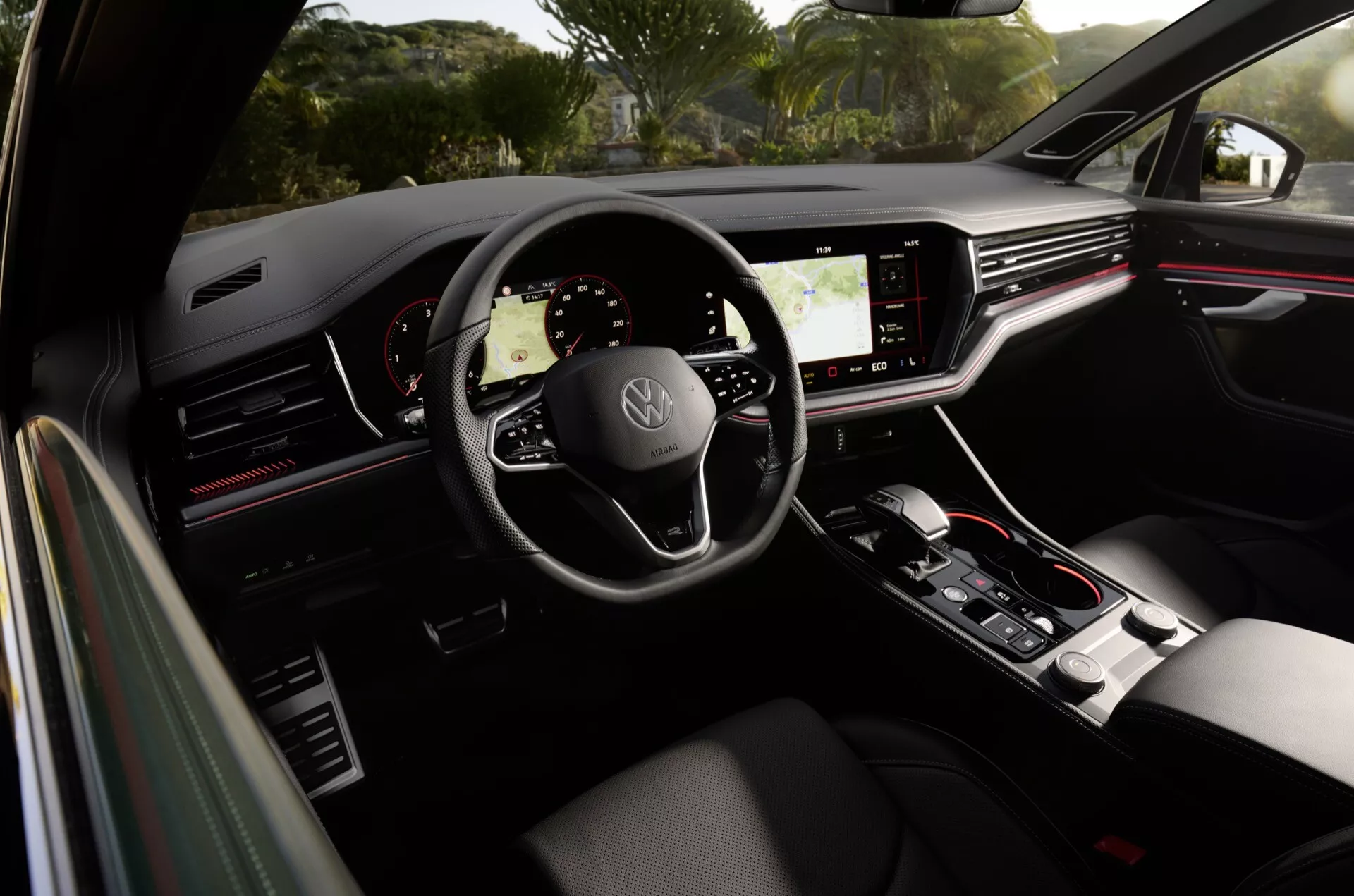 Interiér Volkswagen Touareg 2023 z pohľadu zadného pasažiera ukazujúci volant s logom, digitálny prístrojový panel a dotykovú stredovú konzolu