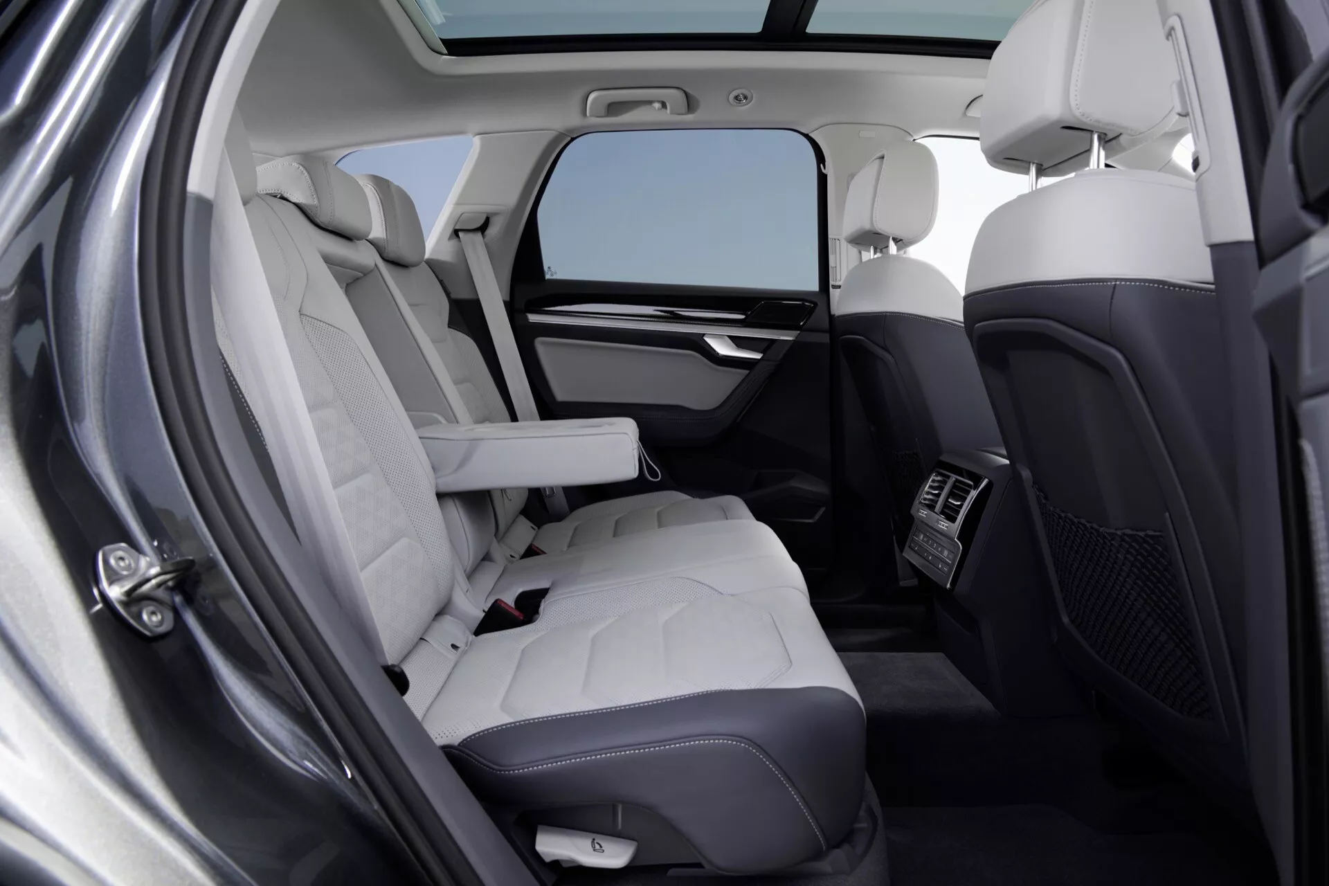 Interiér VW Touareg 2023 (III Facelift) s luxusnými zadnými sedadlami z ľahkej prešívané kože, integrovanými technologickými funkciami a osvetlením prostredníctvom panoramatickej strechy