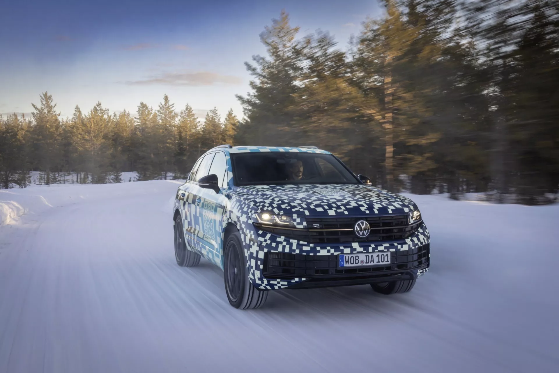 Model VW Touareg III Facelift 2023 zachytený v pohybe na zasneženej krajine, predvádzajúci dynamické schopnosti a pokročilé technologické vlastnosti z perspektívy troch štvrtín spredu