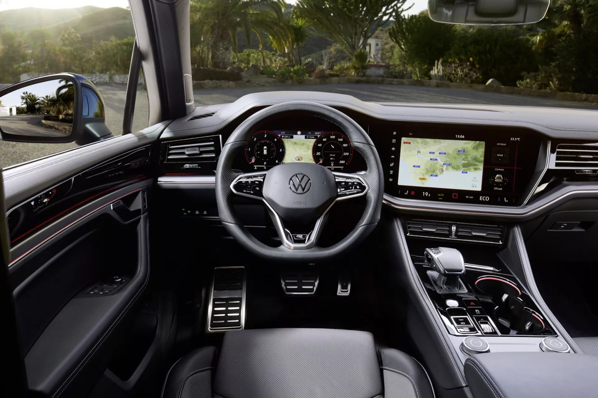 Interiér VW Touareg 2023 so zameraním na multifunkčný volant obalený kožou s logom Volkswagen, digitálne palubnú dosku, dotykový infotainment systém a štýlový volič prevodov v luxusnom prostredí s tmavými tónmi a kovovými akcentmi