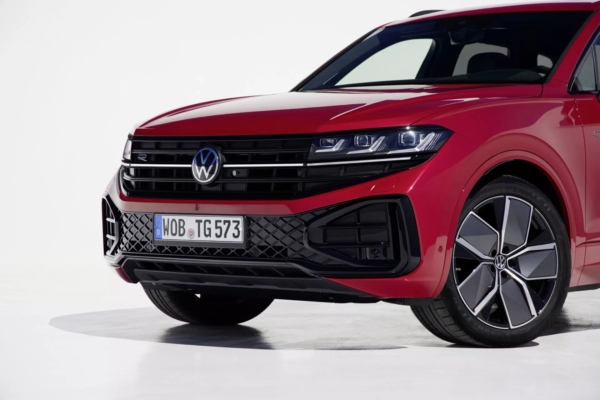 Pohľad zľava spredu na Volkswagen Touareg 2023 zdôrazňujúci jeho LED svetlomety, športovú mriežku a výkonný červený lak