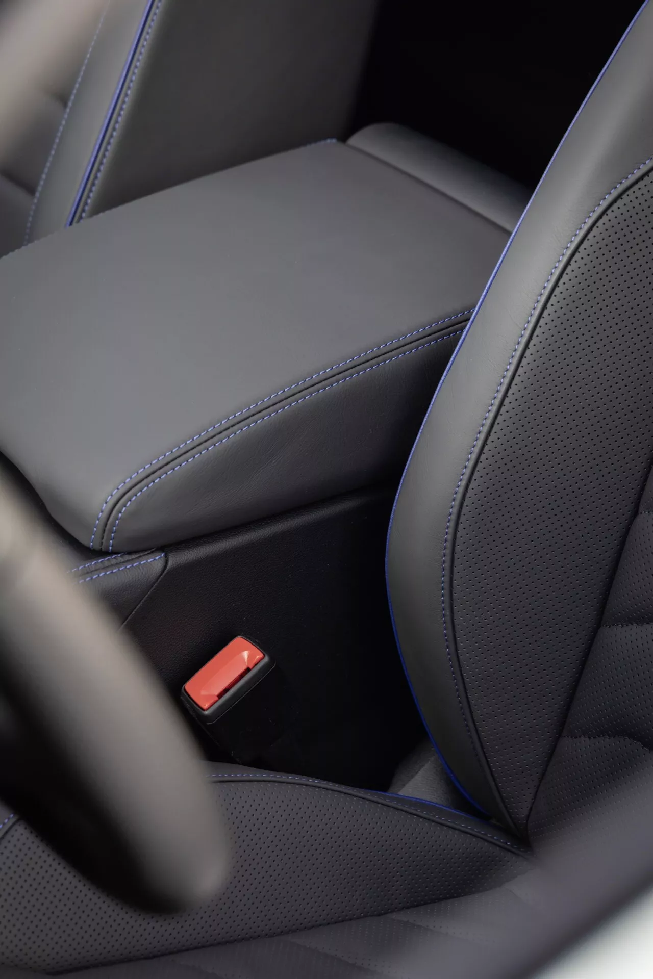 Detailný pohľad na interiér VW Touareg (III facelift) 2023 ukazujúci ergonomický dizajn čierneho koženého sedadla so zdôrazneným prešívaním, perforovaným stredom pre možné kúrenie/chladenie a červenú sponu bezpečnostného pásu, ktorá zdôrazňuje luxusné a bezpečnostné funkcie